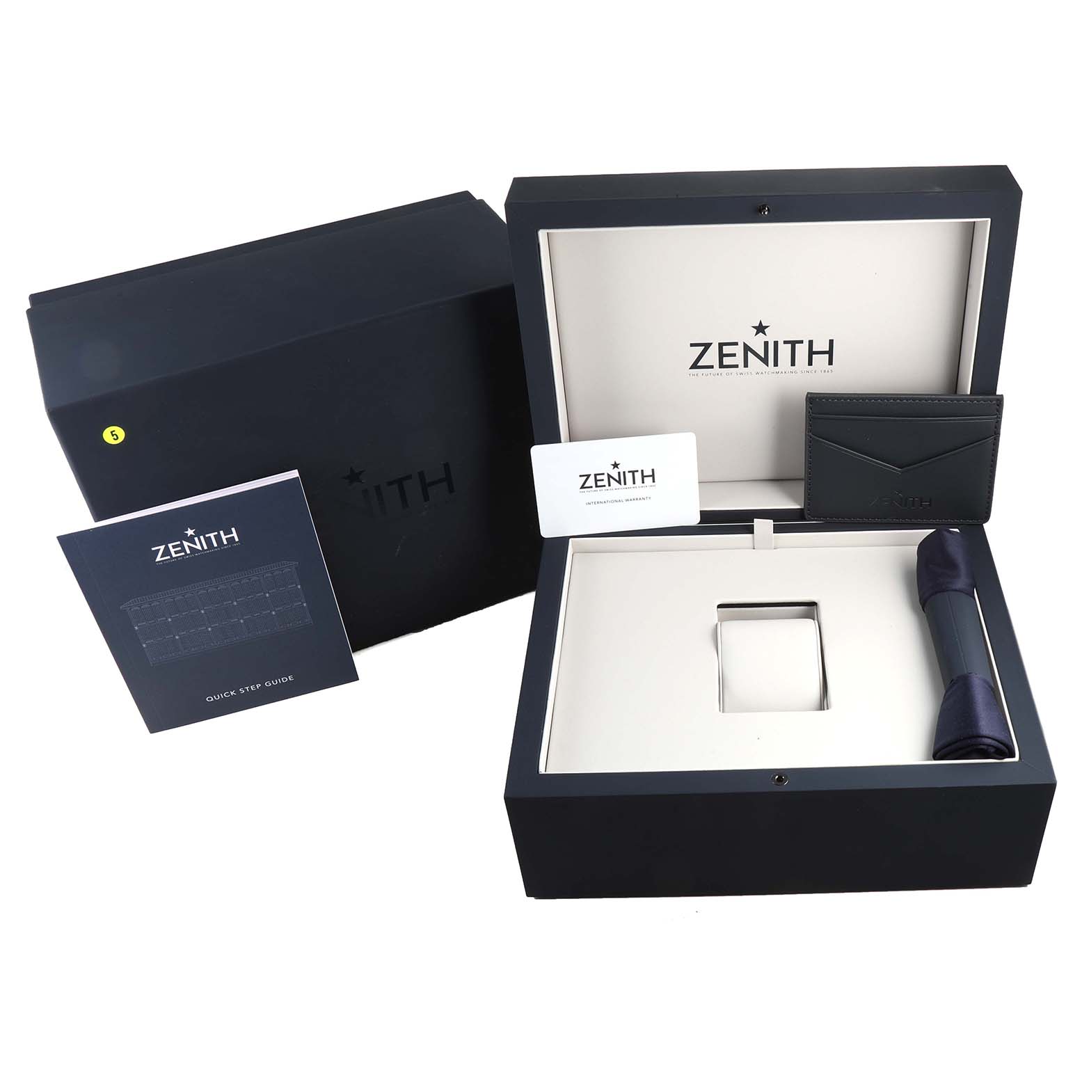 The image shows the packaging and accessories for a Zenith Chronomaster 03.3107.3600/56.M3100 Men
s Stainless Steel Green Dial 03.3107.3600/56.M3100 Men
s Stainless Steel Green Dial watch along with its box, card holder, manual, and cleaning cloth.