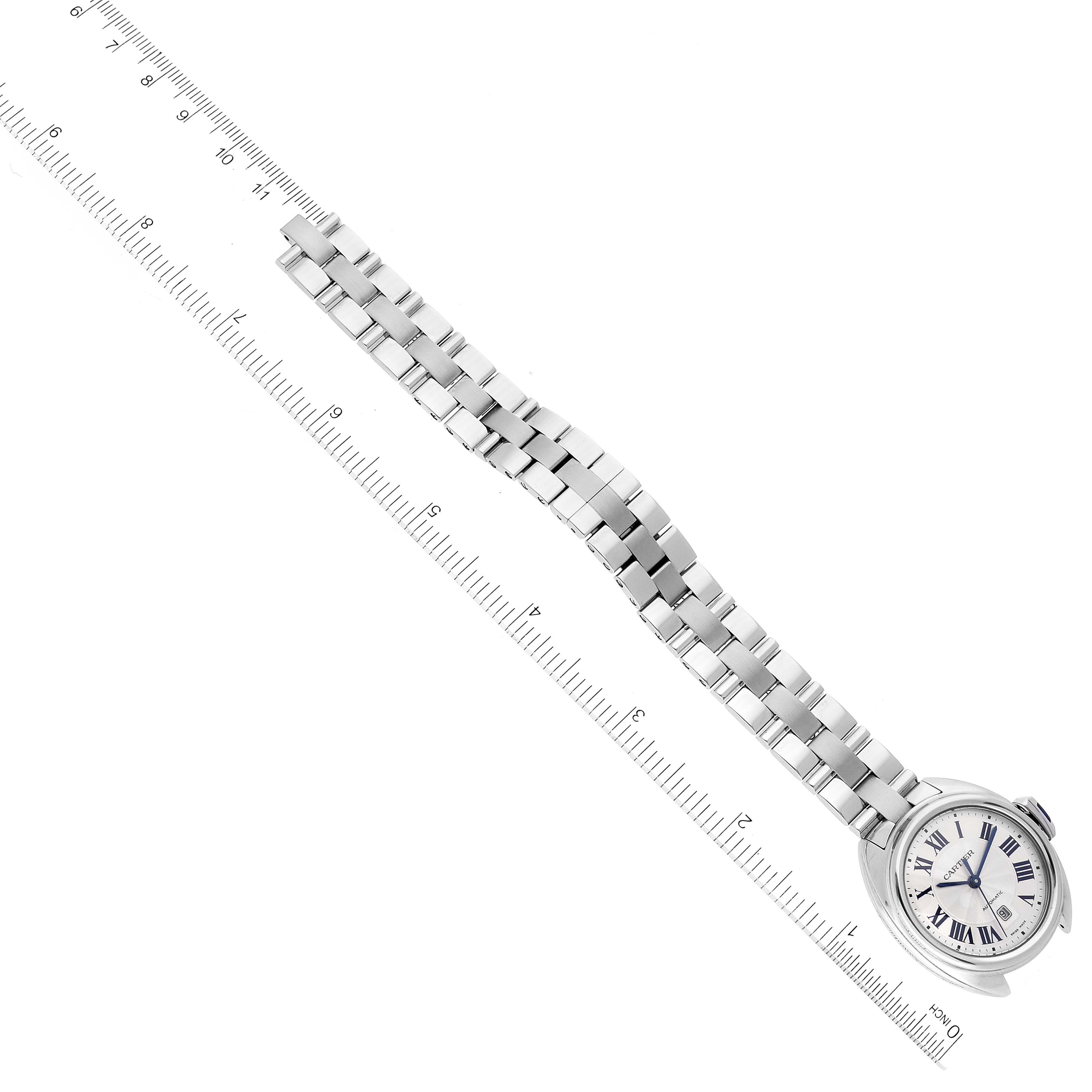 The image shows an overhead view of the Cle model by Cartier, highlighting the face and full bracelet with a ruler for scale.