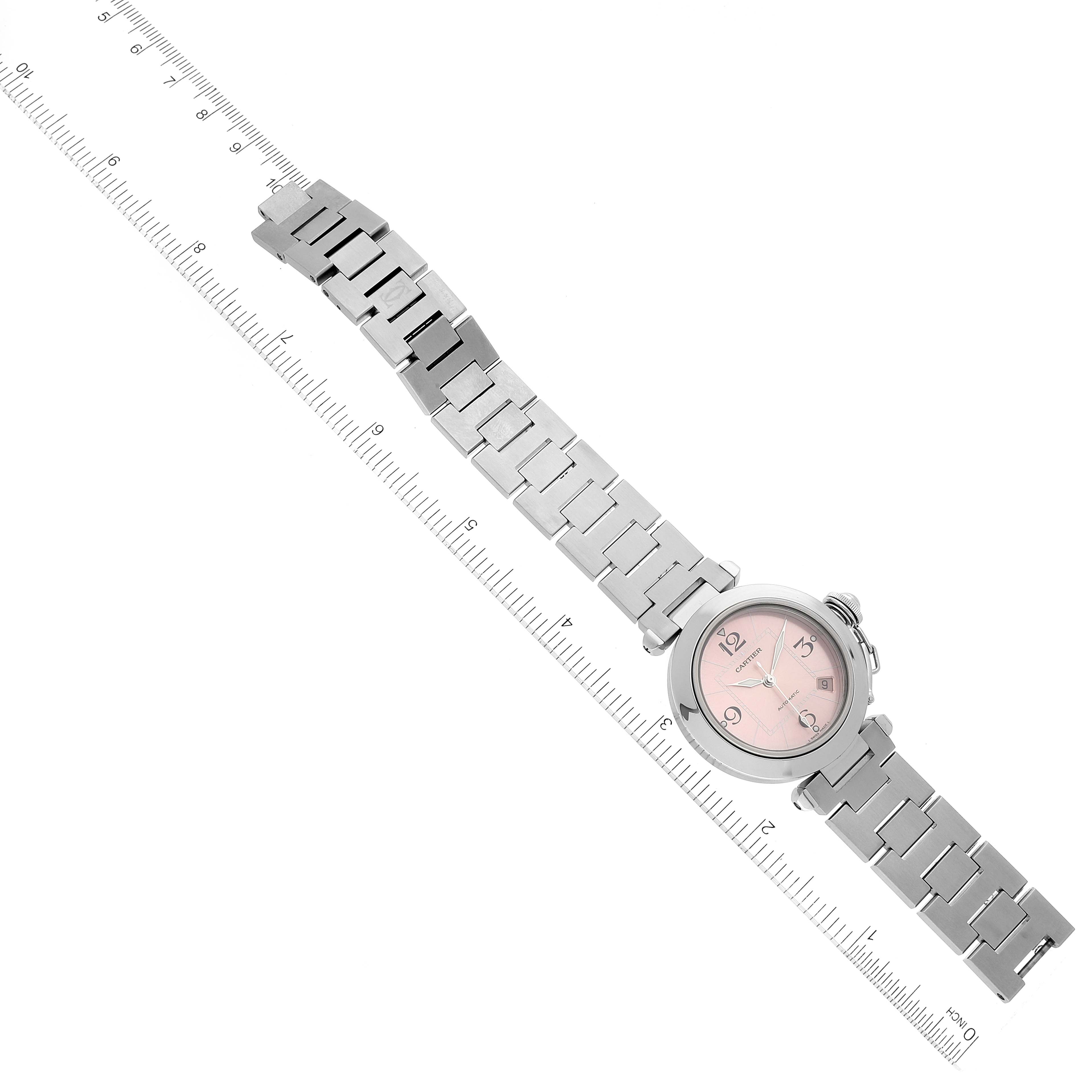 The image shows a Cartier Pasha W31075M7 Women's Stainless Steel Pink Dial W31075M7 Women's Stainless Steel Pink Dial watch laid flat, with its face and metal bracelet visible next to a measurement ruler.