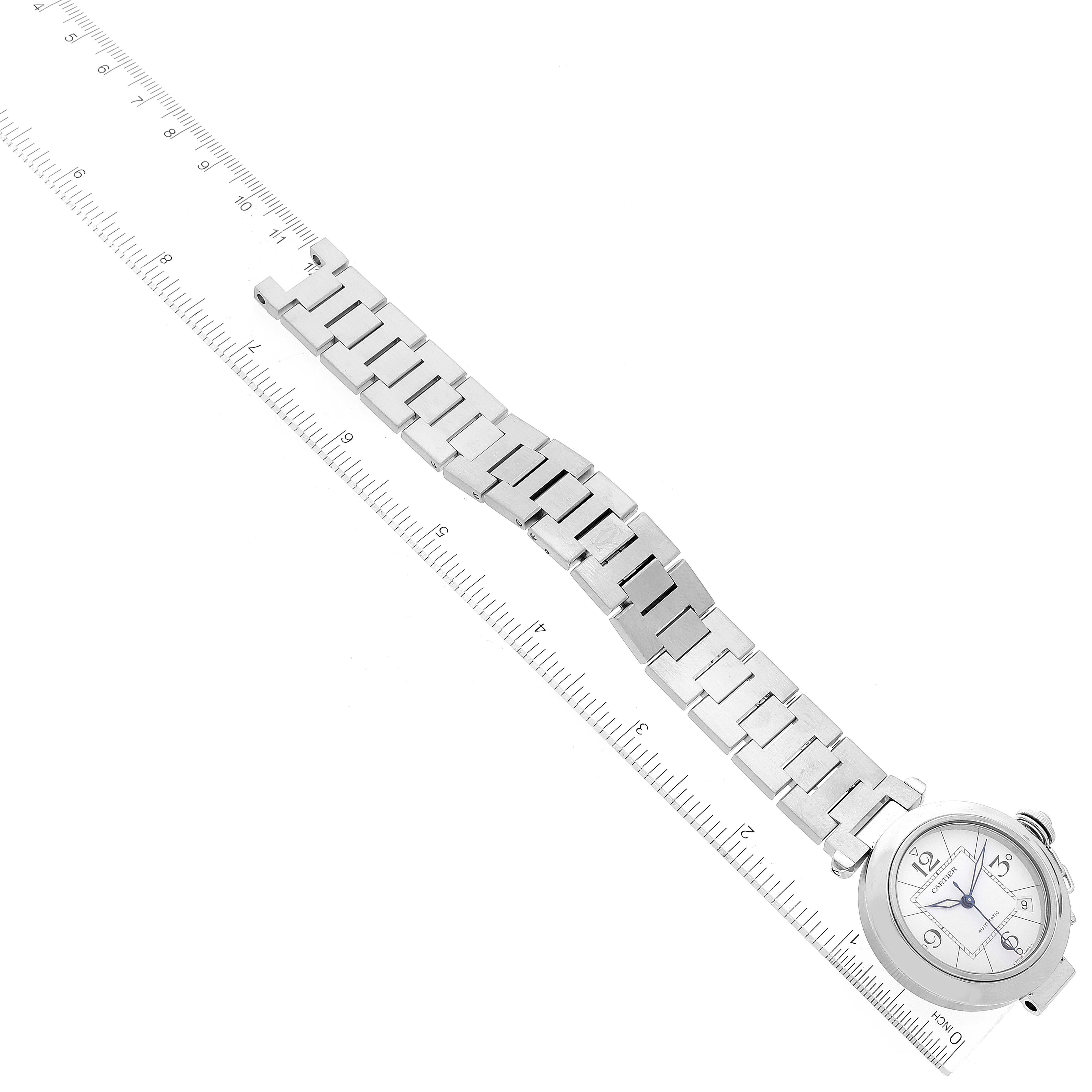 The image shows a Cartier Pasha W31074M7 Men's Stainless Steel White Dial W31074M7 Men's Stainless Steel White Dial watch laid flat with its metal bracelet alongside a ruler for measurement.