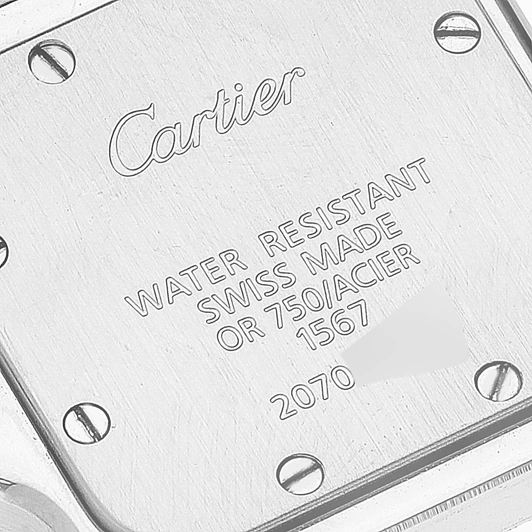The image shows the back case of a Santos watch by Cartier, featuring engraved text and screws.