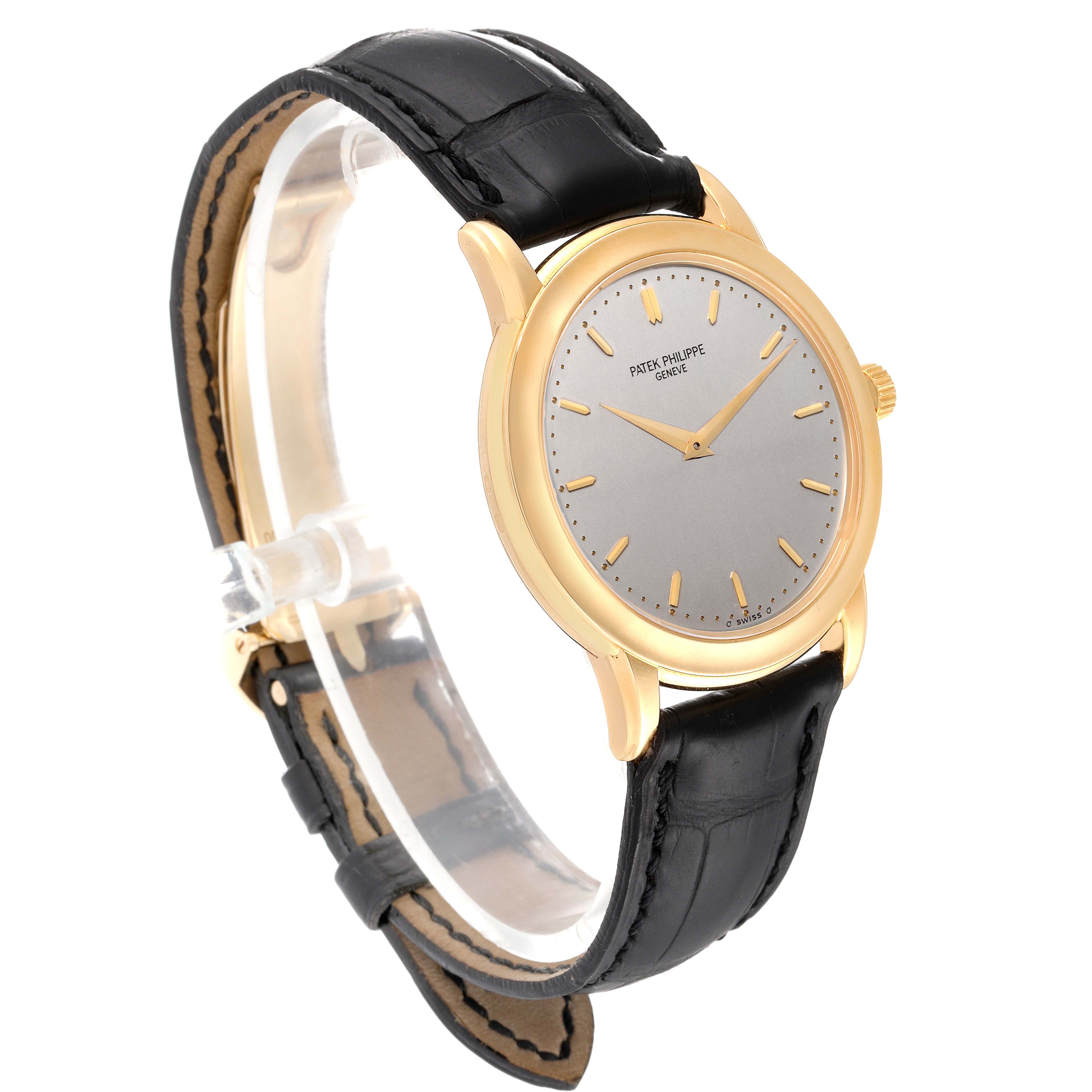 The Patek Philippe Calatrava 5032J Men's Yellow Gold Silver Dial 5032J Men's Yellow Gold Silver Dial watch is shown in a three-quarter view, highlighting its gold case, dial, and black leather strap.