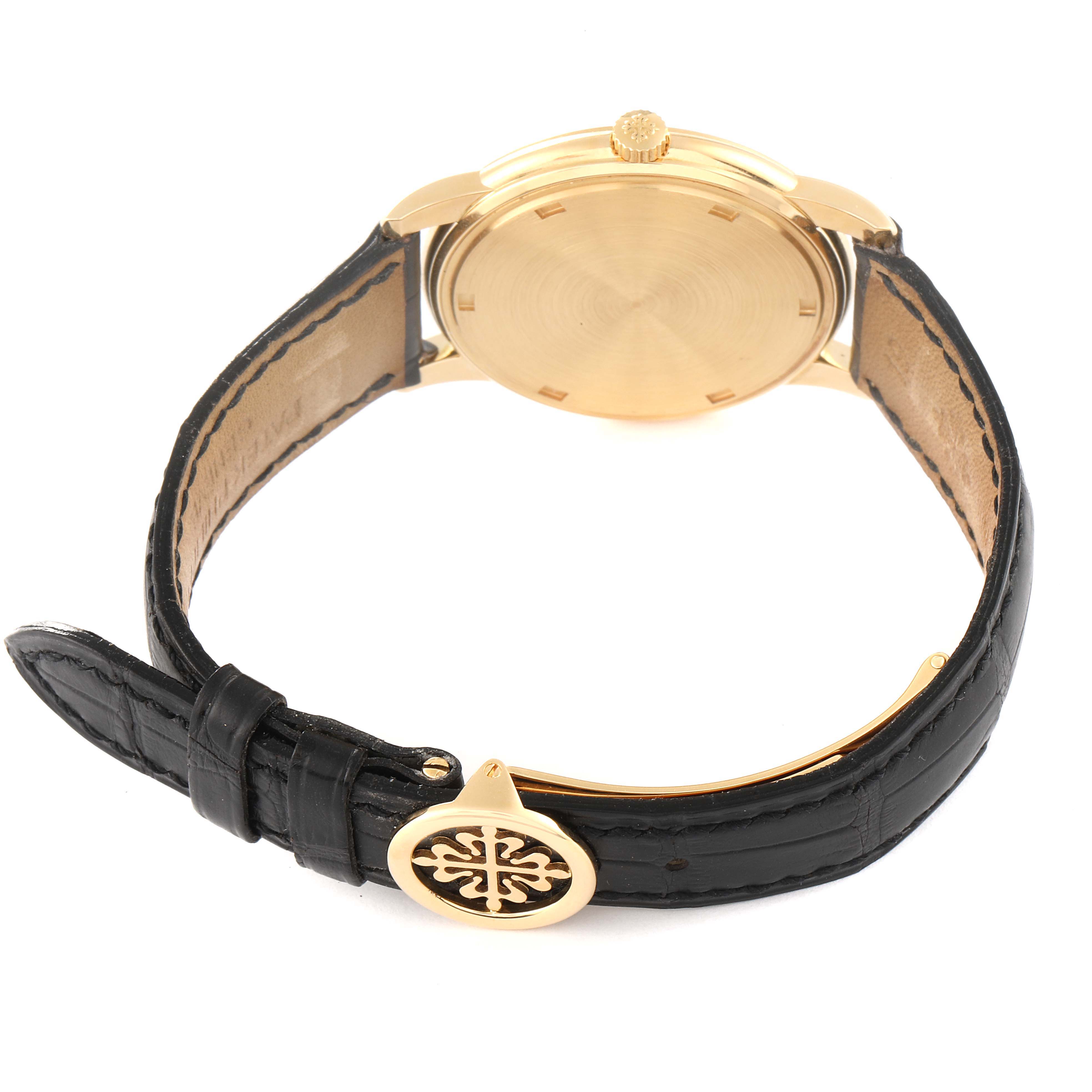 The image shows the rear view of a Patek Philippe Calatrava 5032J Men's Yellow Gold Silver Dial 5032J Men's Yellow Gold Silver Dial watch, highlighting its case back, crown, and leather strap with a distinctive emblem.