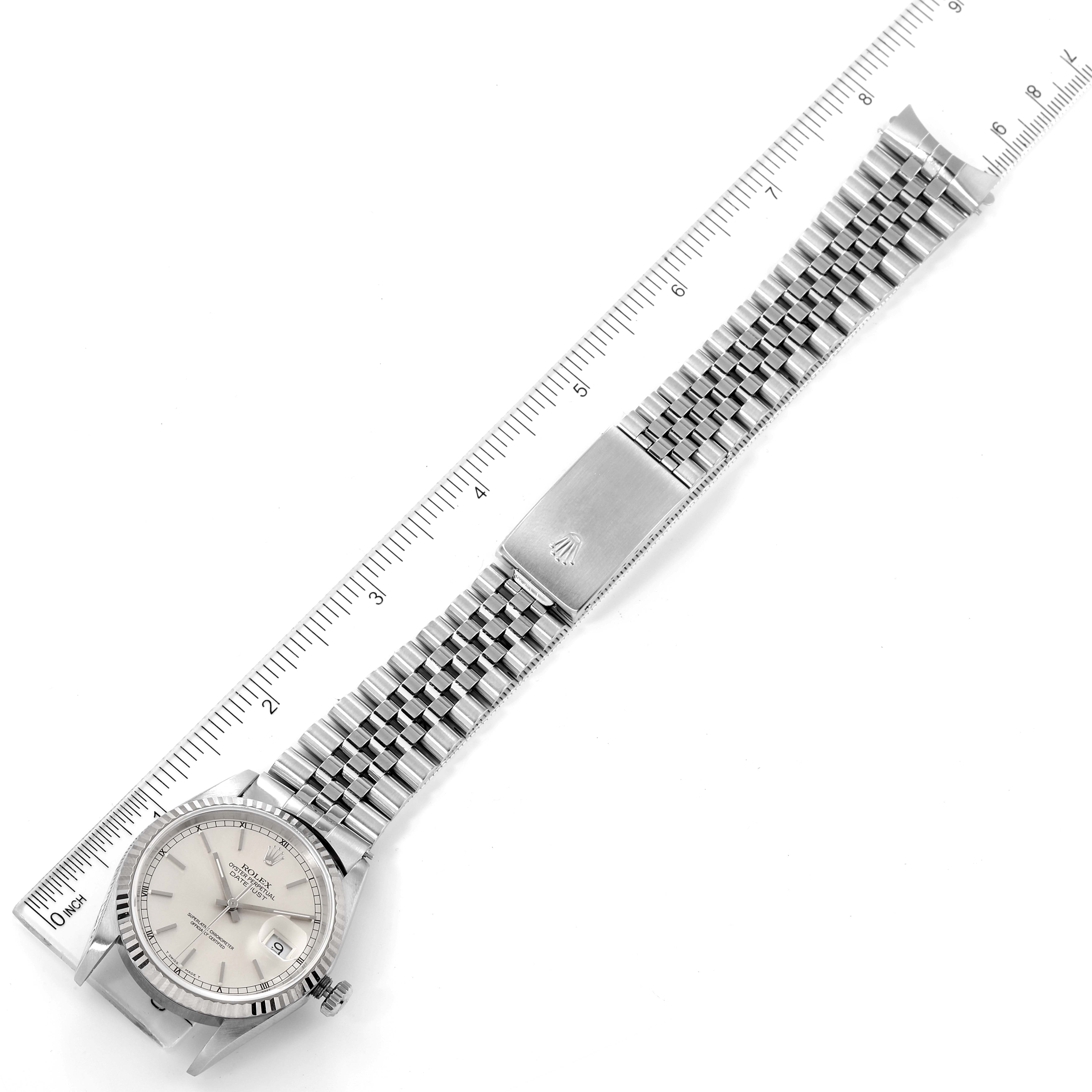 The Rolex Datejust 16234 Men's Stainless Steel Silver Dial 16234 Men's Stainless Steel Silver Dial watch is shown from a top-down angle, displaying its face, bracelet, and clasp, with a ruler for scale.