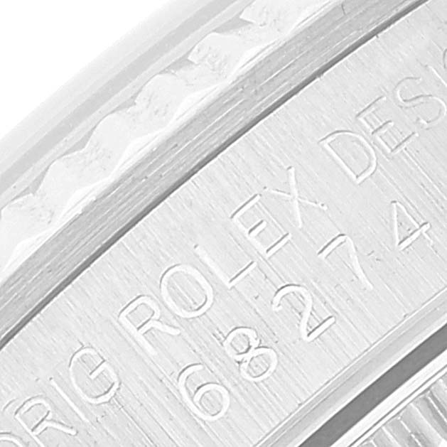 This image shows an angled close-up of the serial number engraving on the bezel of a Mid-Size Rolex watch.