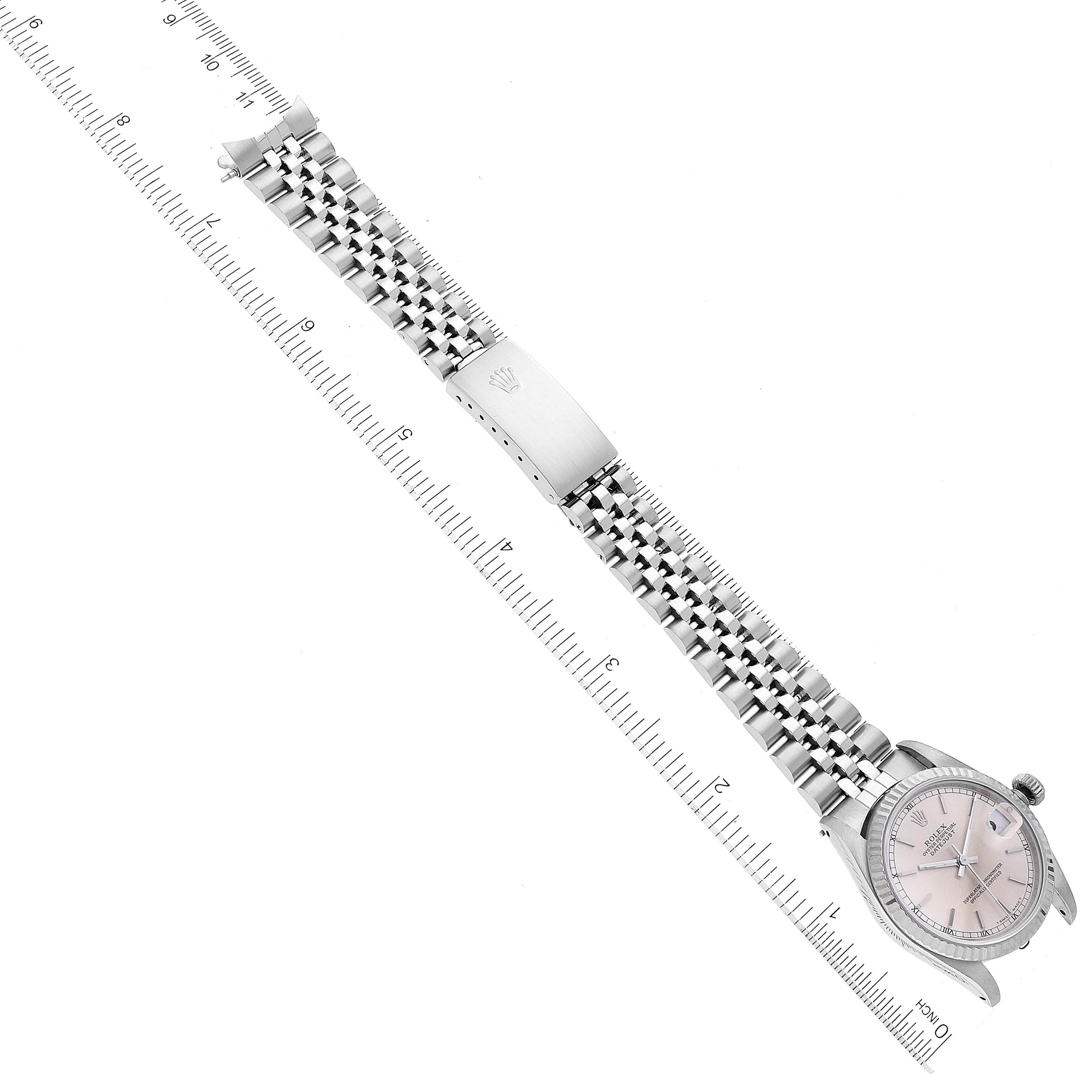 The image shows a top view of a Mid-Size Rolex watch with its face, bracelet, and clasp, alongside a ruler for measurement.