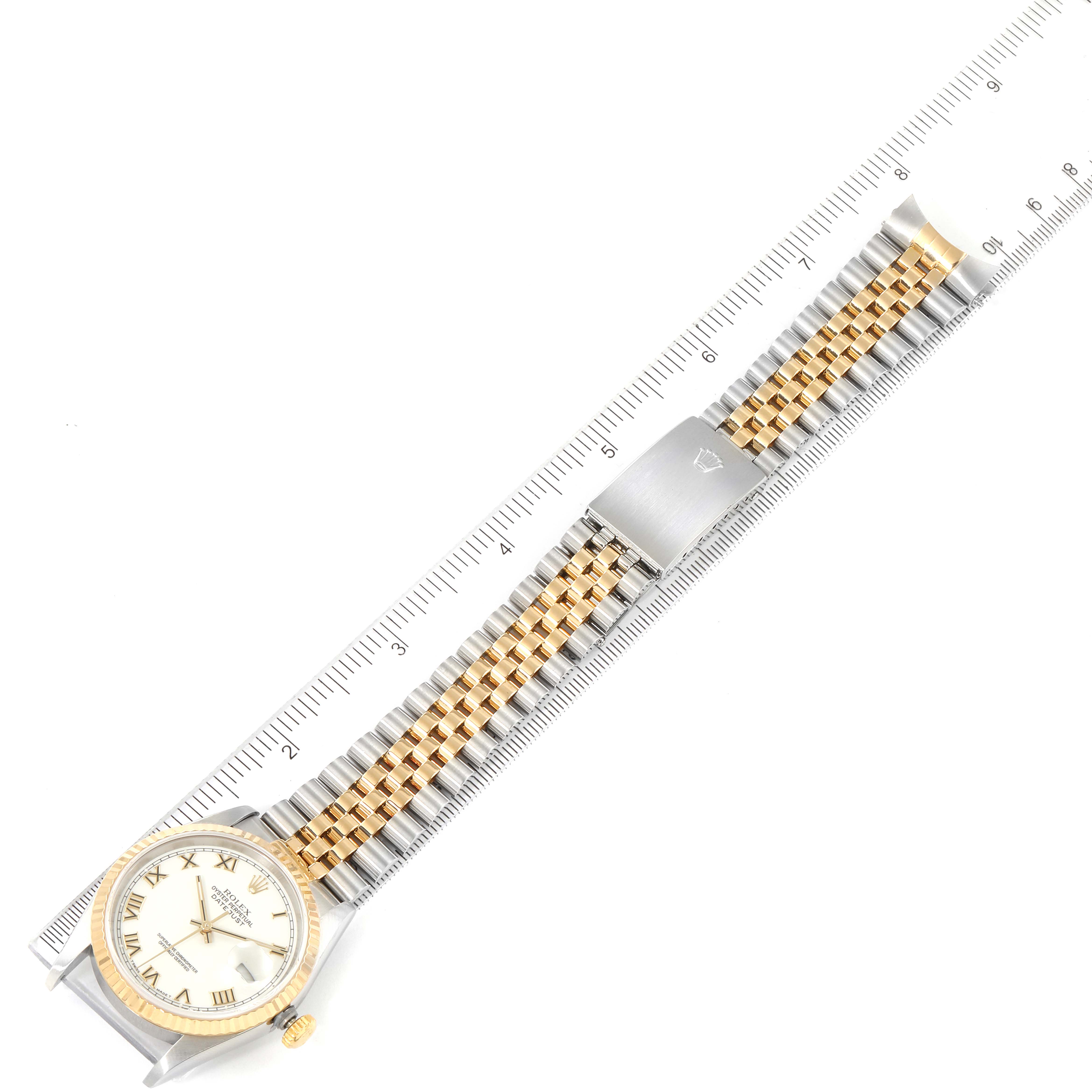 The Rolex Datejust 16233 Men's Steel and Gold (two tone) White Dial 16233 Men's Steel and Gold (two tone) White Dial watch is shown from a top-down angle, displaying the dial, case, and full bracelet with a ruler for scale.