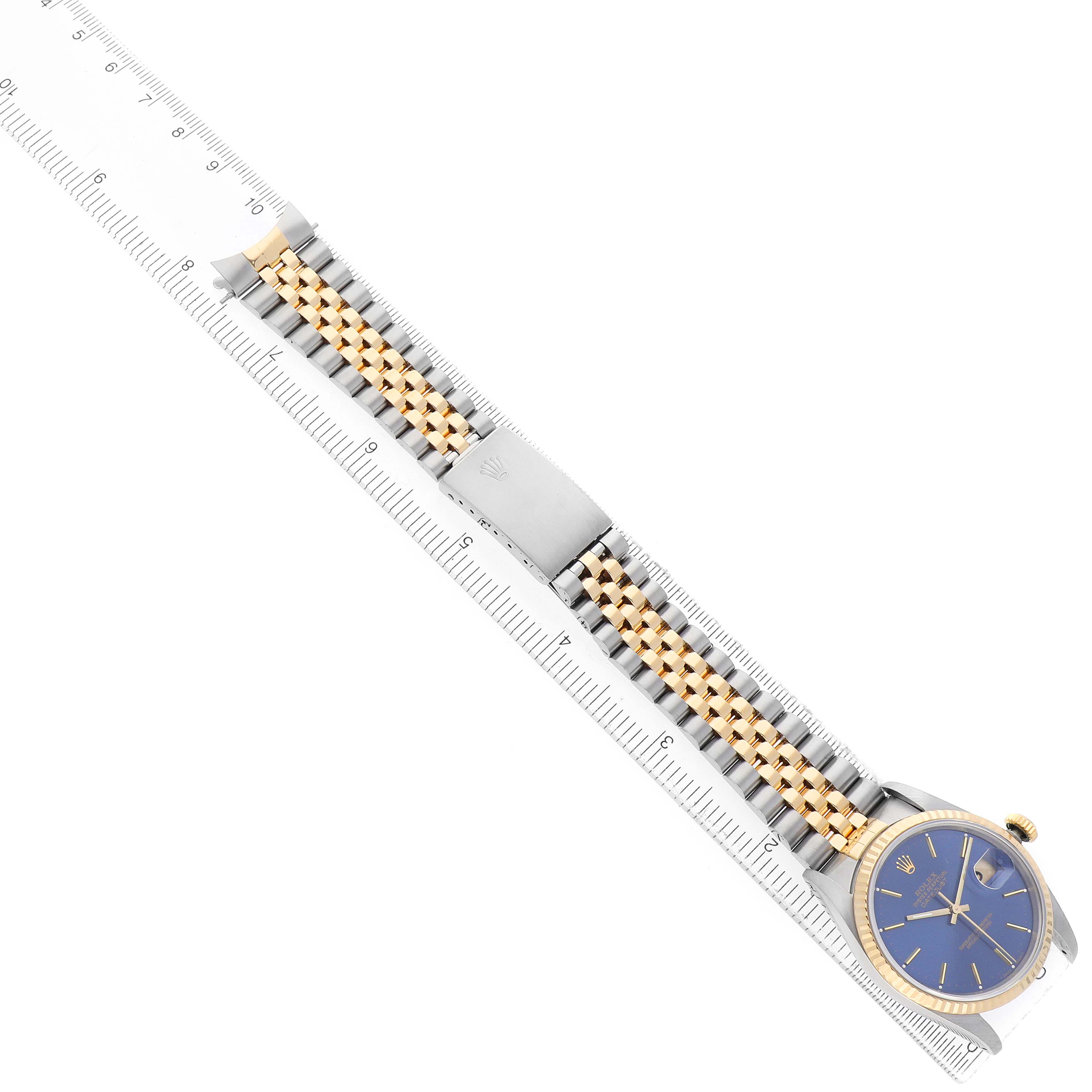 The Rolex Datejust 16233 Men's Steel and Gold (two tone) Blue Dial watch is shown from a top angle, displaying the full bracelet and dial aligned on a ruler.