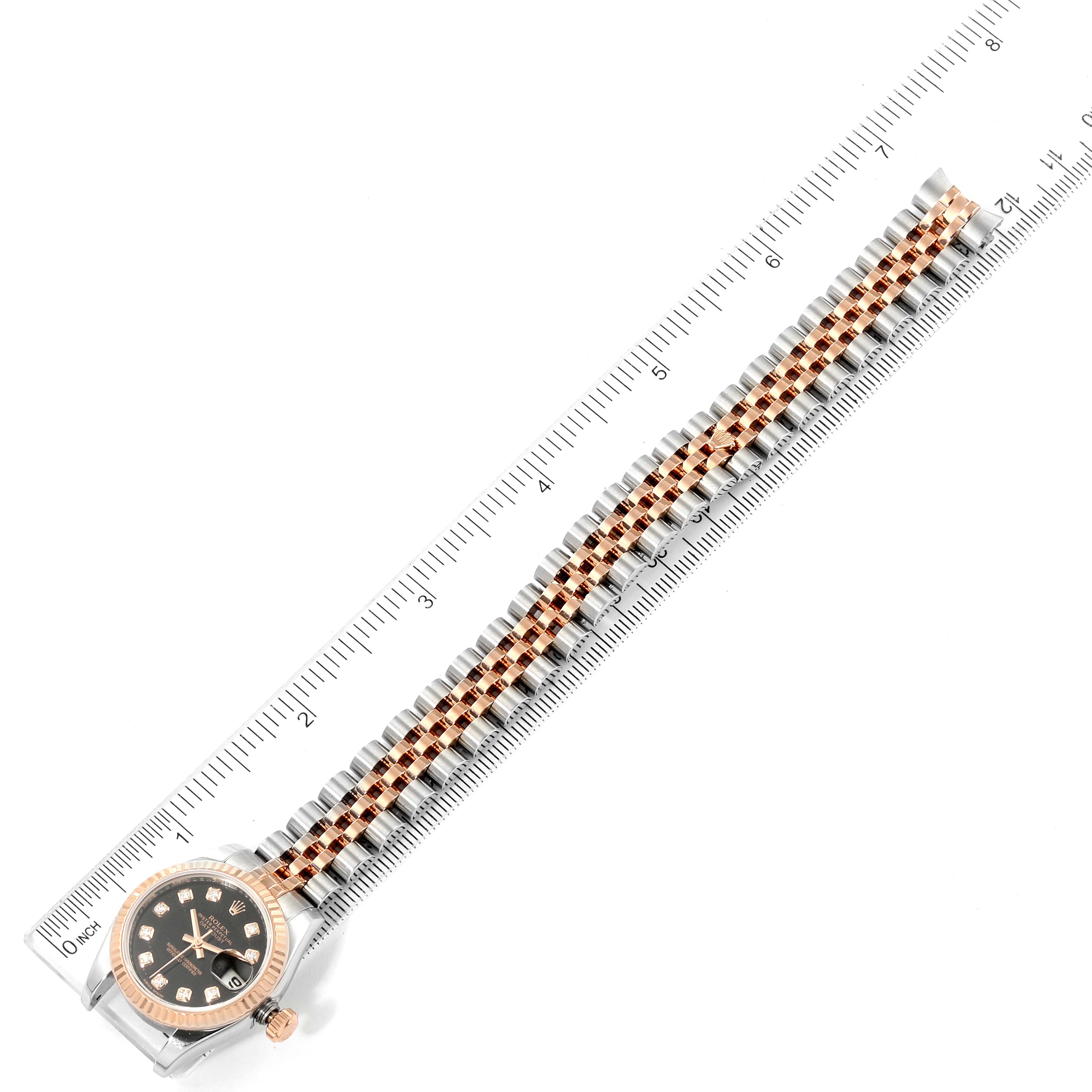 The image shows a top-down view of a Rolex Datejust 179171 Women's Steel and Gold (two tone) Black Dial 179171 Women's Steel and Gold (two tone) Black Dial watch with the face and entire band visible next to a ruler for measurement.