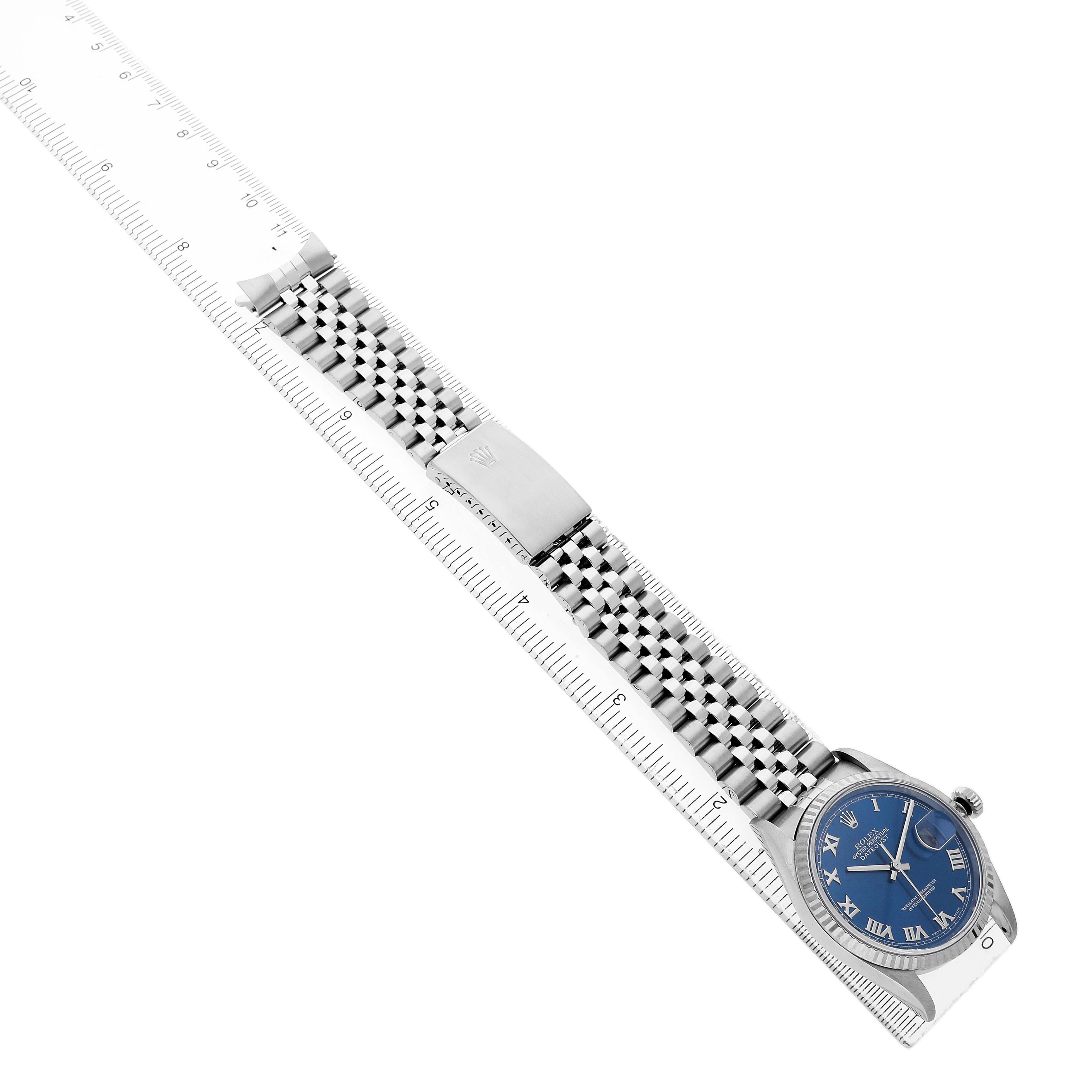 The Rolex Datejust 16234 Men's Stainless Steel Blue Dial watch is shown angled diagonally, displaying the face, bracelet, and clasp alongside a ruler for scale.