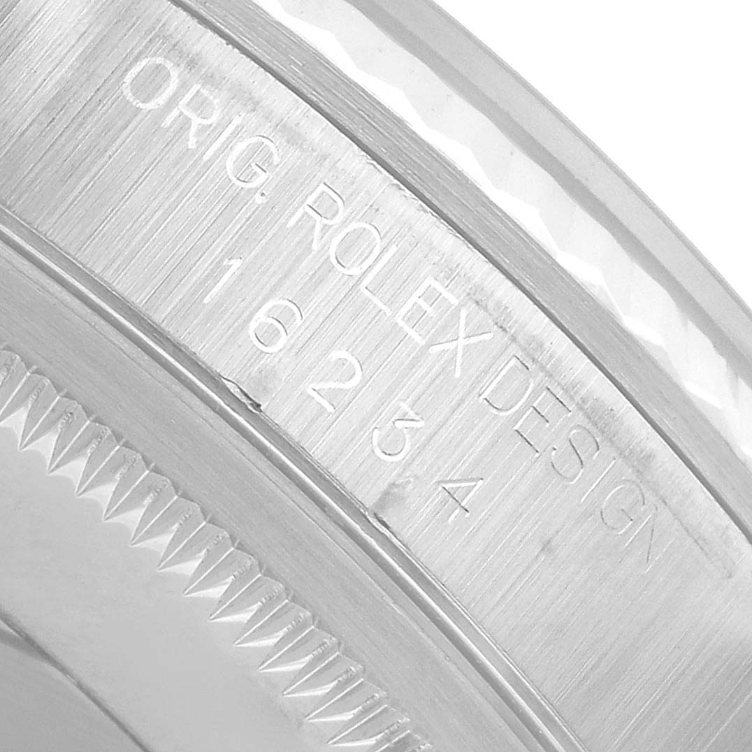 The image shows a close-up of the engraved case edge and serial number on a Rolex Datejust 16234 Men's Stainless Steel Blue Dial watch.