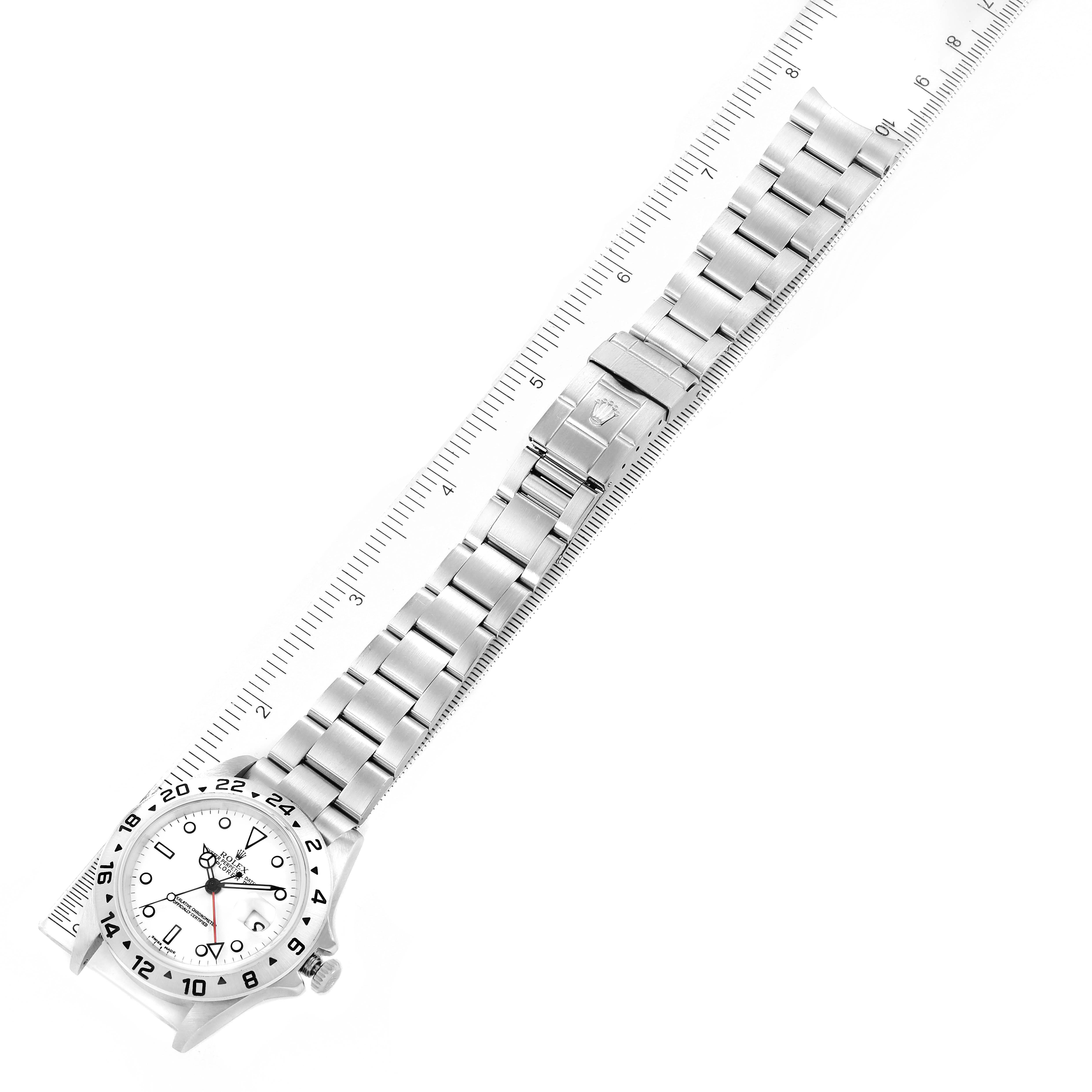 The image shows a top-down view of a Rolex Explorer 16570 Men
s Stainless Steel White Dial 16570 Men
s Stainless Steel White Dial watch with its full metal bracelet and clasp, placed alongside a ruler.