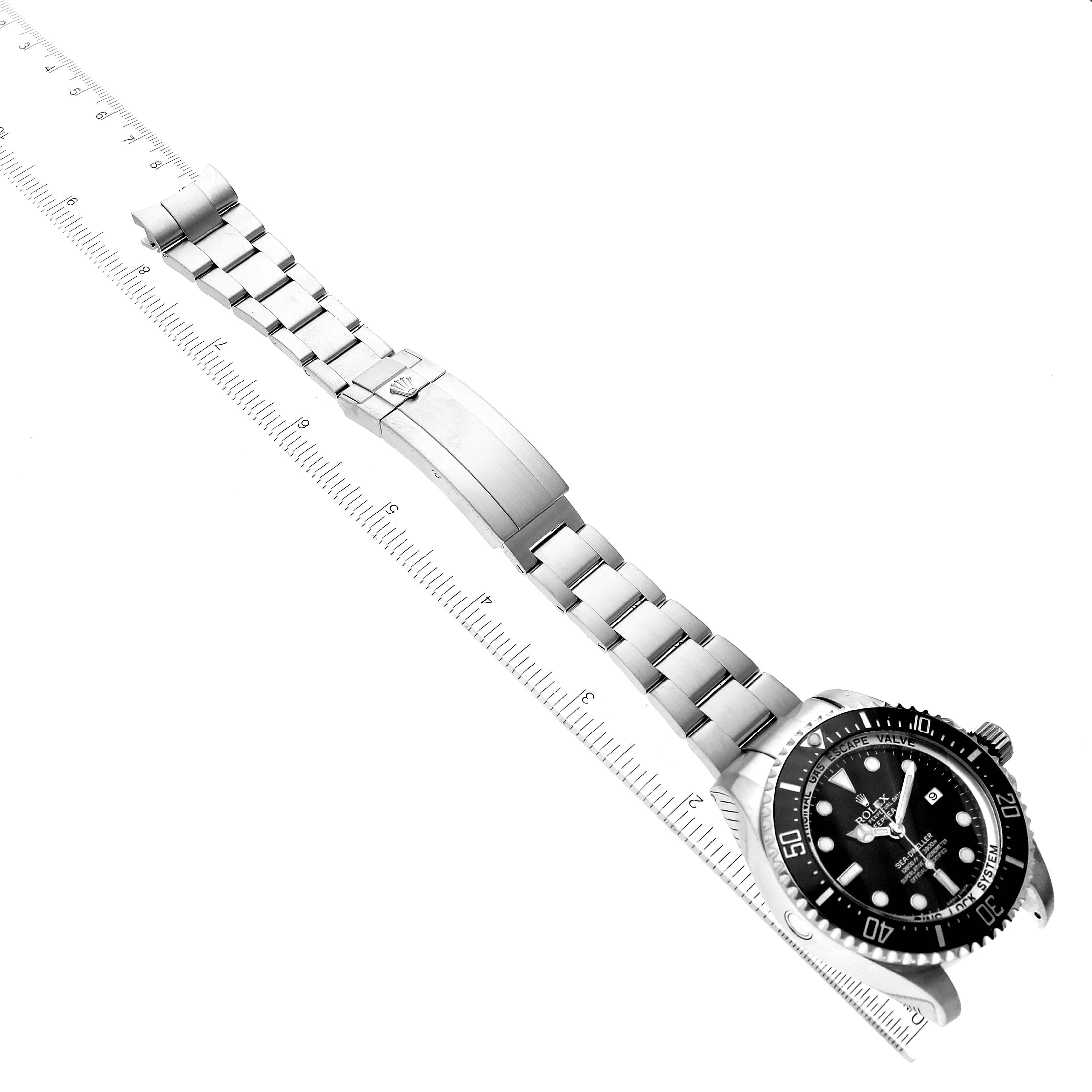 This image shows the Rolex Sea-Dweller 116660 Men
s Stainless Steel Black Dial 116660 Men
s Stainless Steel Black Dial watch at an angle featuring the face, bezel, and full stainless steel bracelet with a ruler for scale.