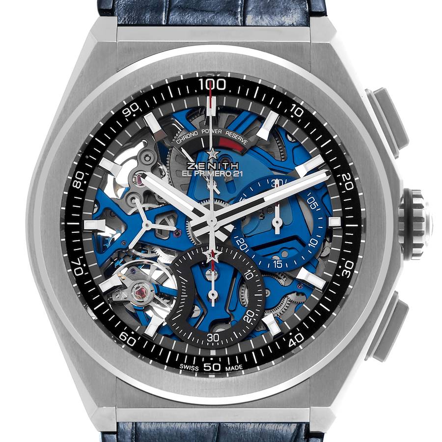 The Zenith El Primero watch is shown from a top-down angle, highlighting its skeleton dial and chronograph features.