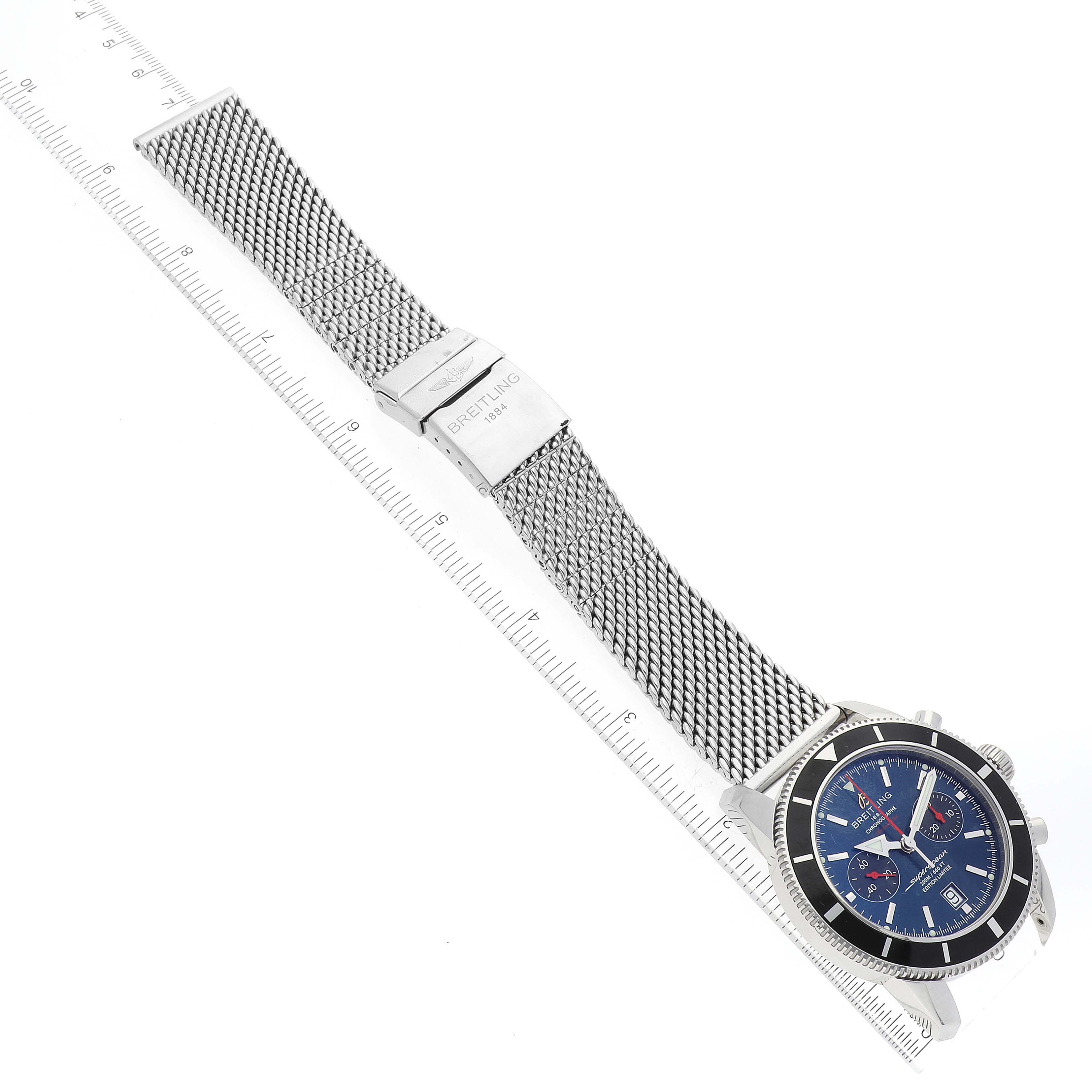 The image shows a front angle of the Breitling Limited Series watch, featuring a blue dial, stainless steel mesh bracelet, and clasp with logo.