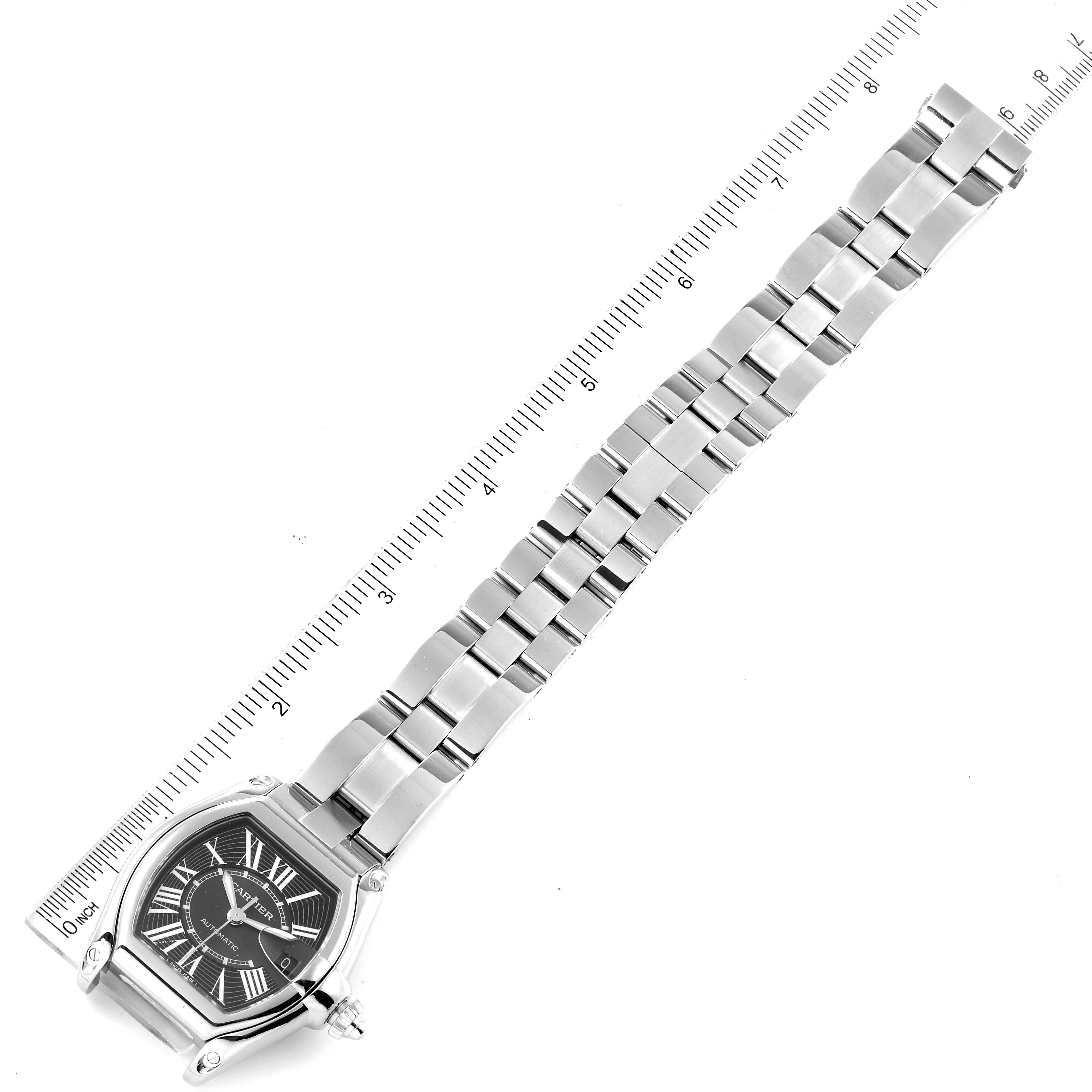 The image shows a Cartier Roadster W62041V3 Men
s Stainless Steel Black Dial W62041V3 Men
s Stainless Steel Black Dial watch laid flat, displaying the face, bracelet, and a ruler for scale.