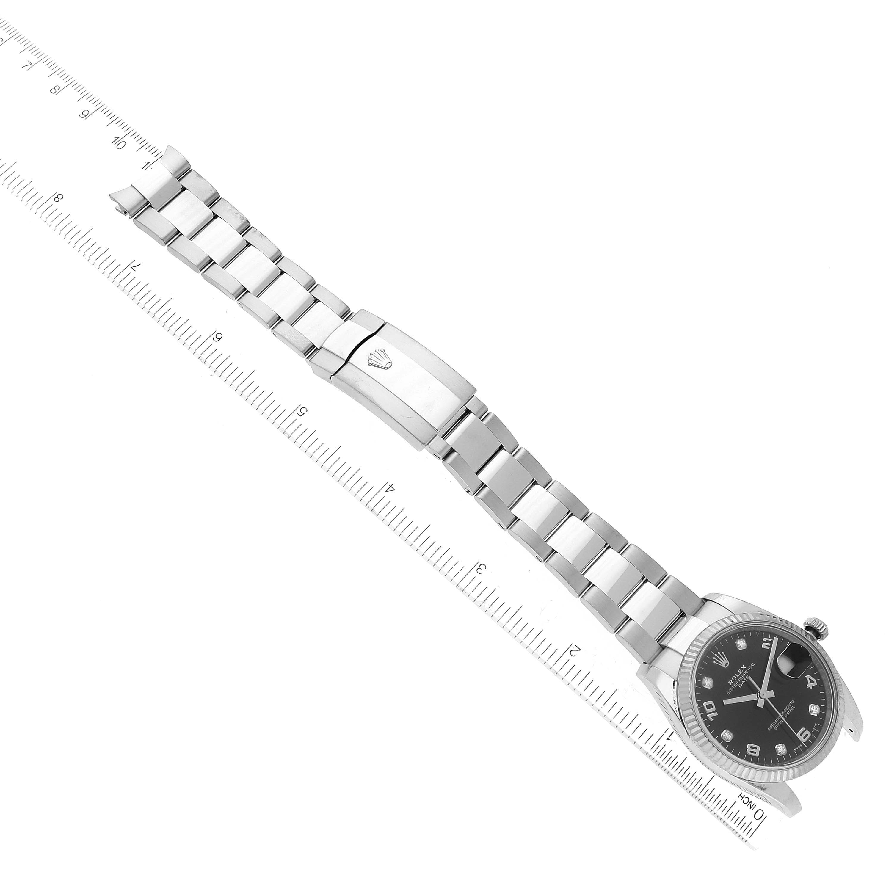 The image shows a Rolex Date 115234 Men's Stainless Steel Black Dial 115234 Men's Stainless Steel Black Dial model watch laid flat, highlighting its stainless steel bracelet and clasp with a ruler for scale.