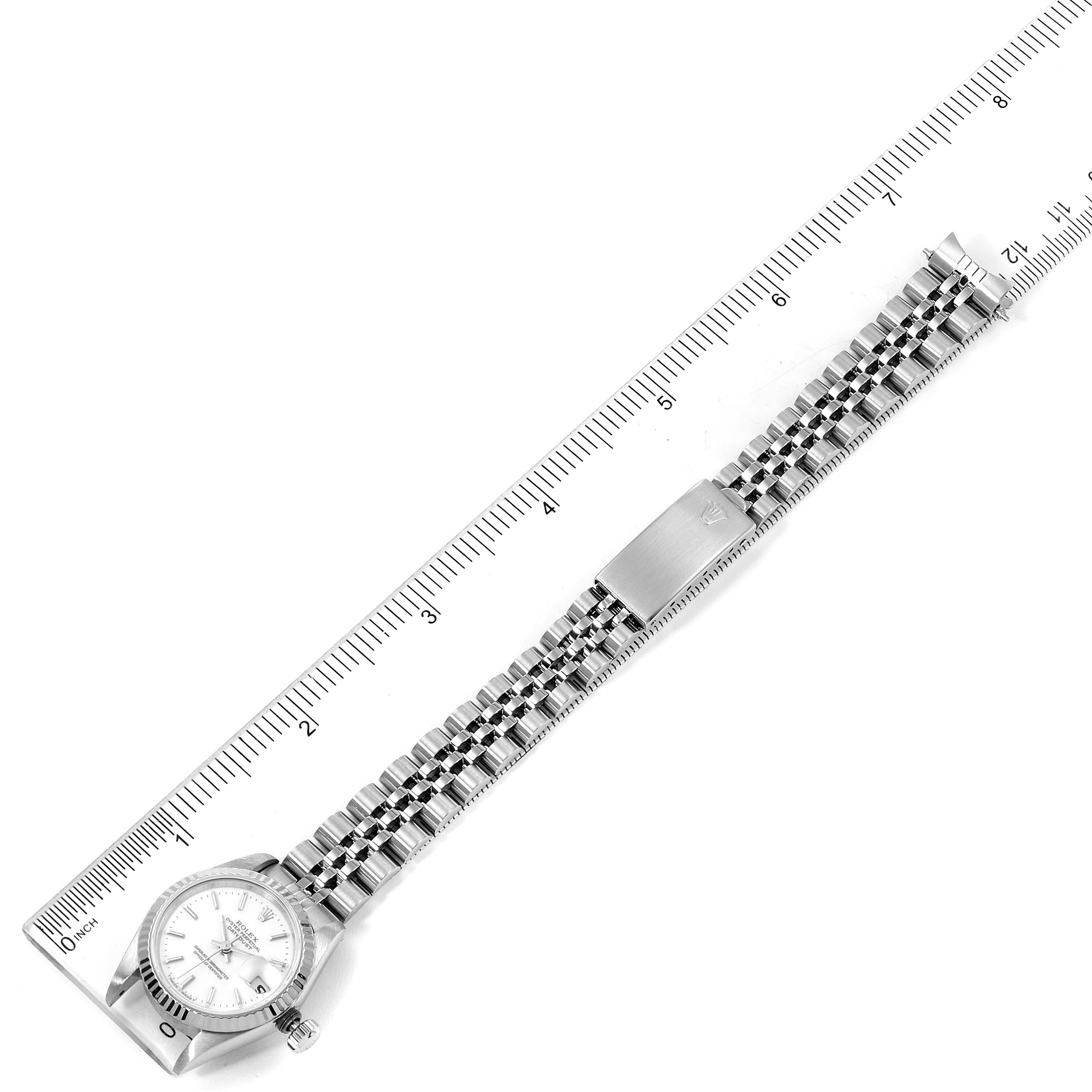The Rolex Datejust 69174 Women
s Stainless Steel White Dial 69174 Women
s Stainless Steel White Dial watch is shown from a top view, displaying the entire bracelet and clasp alongside a ruler for scale.