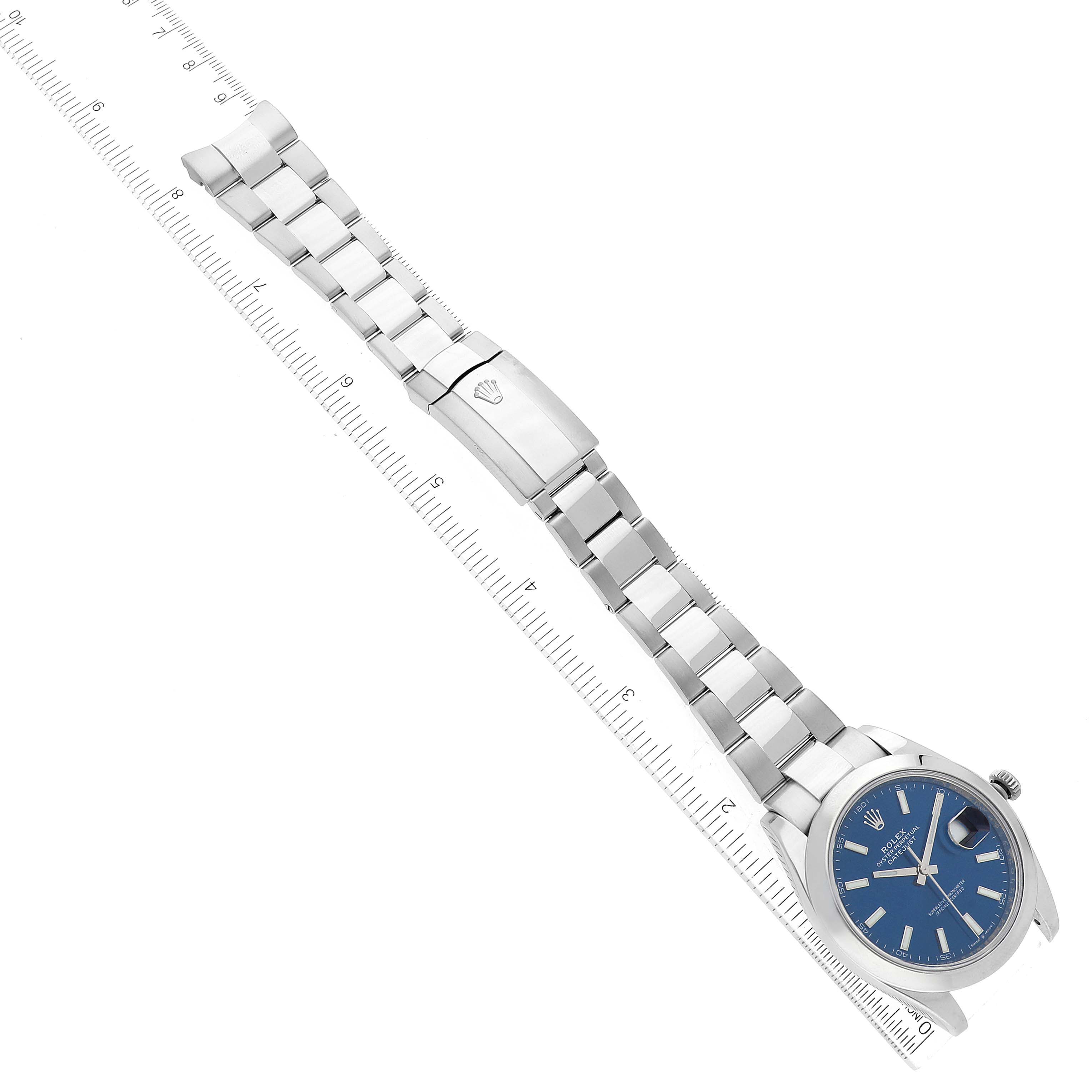 The image shows a top-down view of a Rolex Datejust 41 126300 Men
s Stainless Steel Blue Dial 126300 Men
s Stainless Steel Blue Dial watch with a blue dial and an Oyster bracelet next to a ruler.