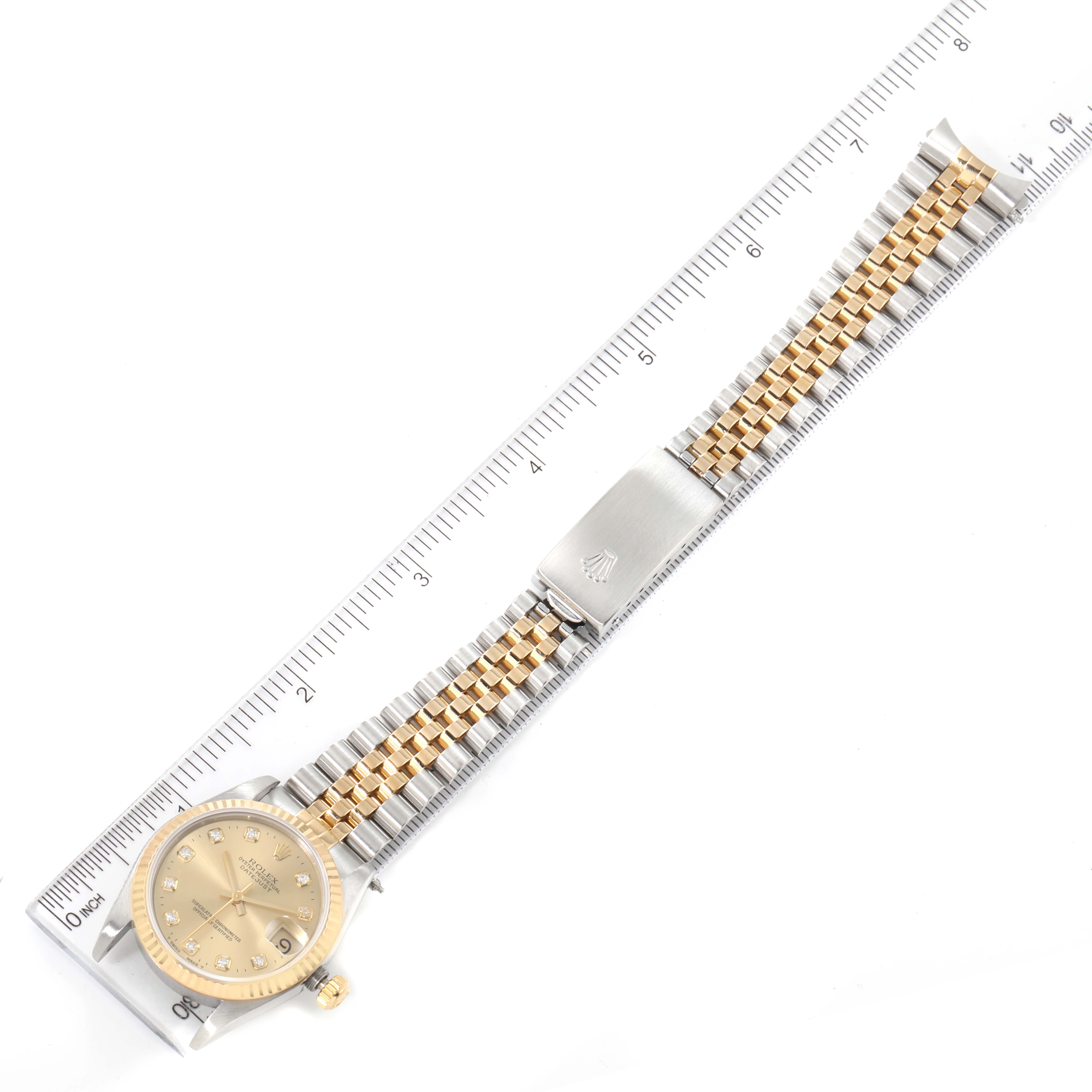 The image shows a top view of a Mid-Size Rolex watch, displaying the dial, bracelet, and clasp against a ruler for measurement.