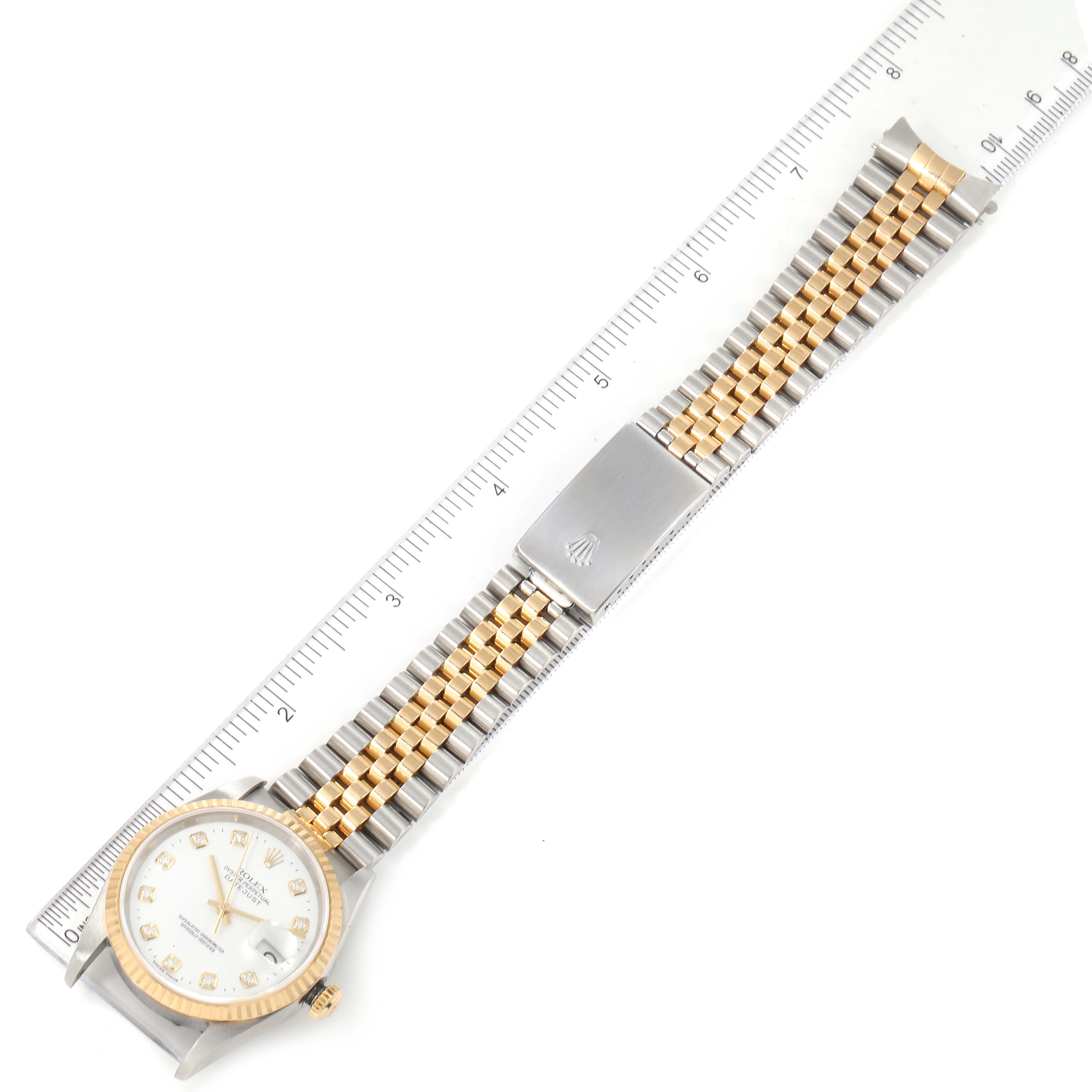 The image shows a Rolex Datejust 16233 Men's Steel and Gold (two tone) White Dial 16233 Men's Steel and Gold (two tone) White Dial watch laid flat, revealing its face, bezel, and jubilee bracelet next to a ruler.