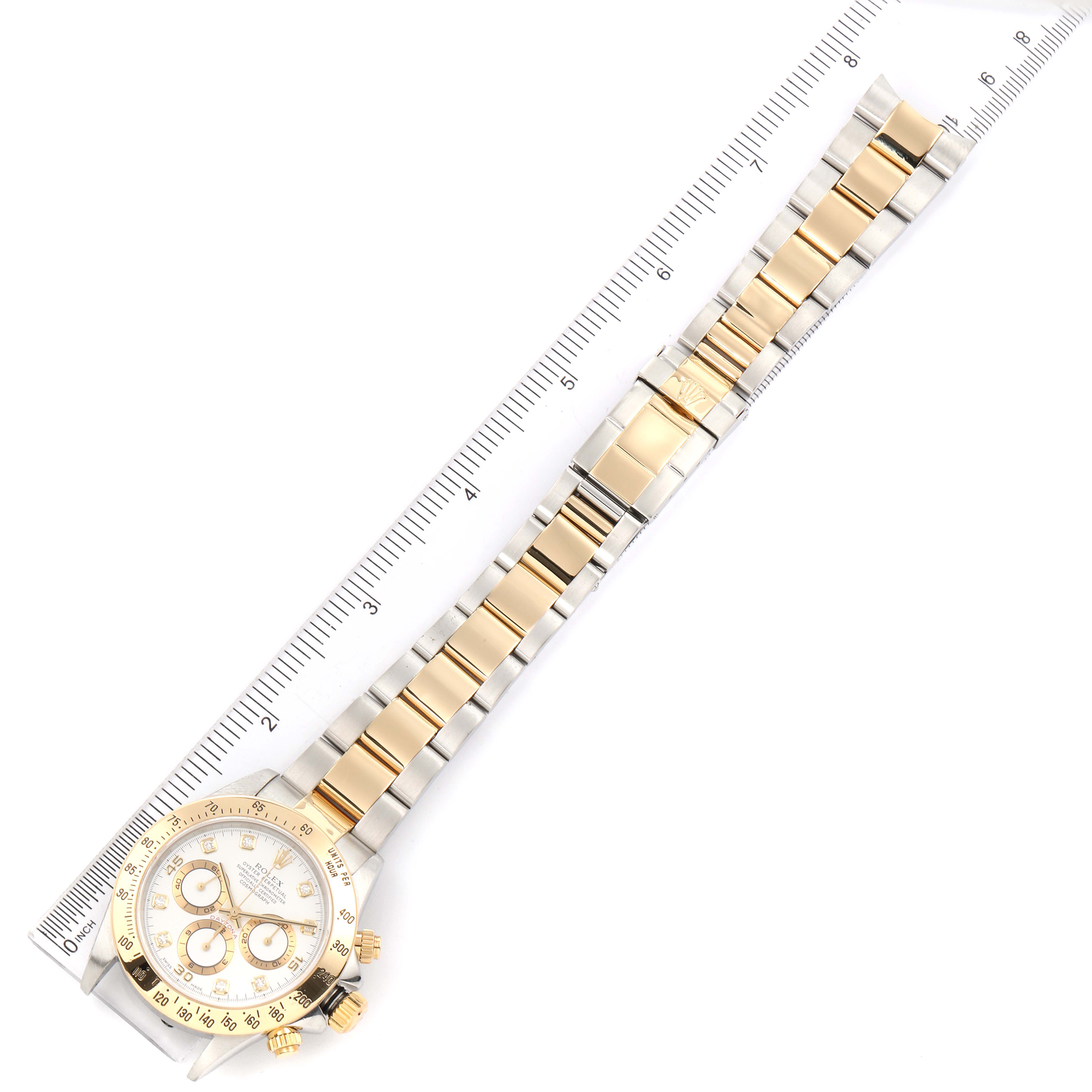 This image shows a Rolex Daytona 16523 Men's Steel and Gold (two tone) White Dial 16523 Men's Steel and Gold (two tone) White Dial watch laid flat with its gold and silver bracelet fully extended alongside a ruler.