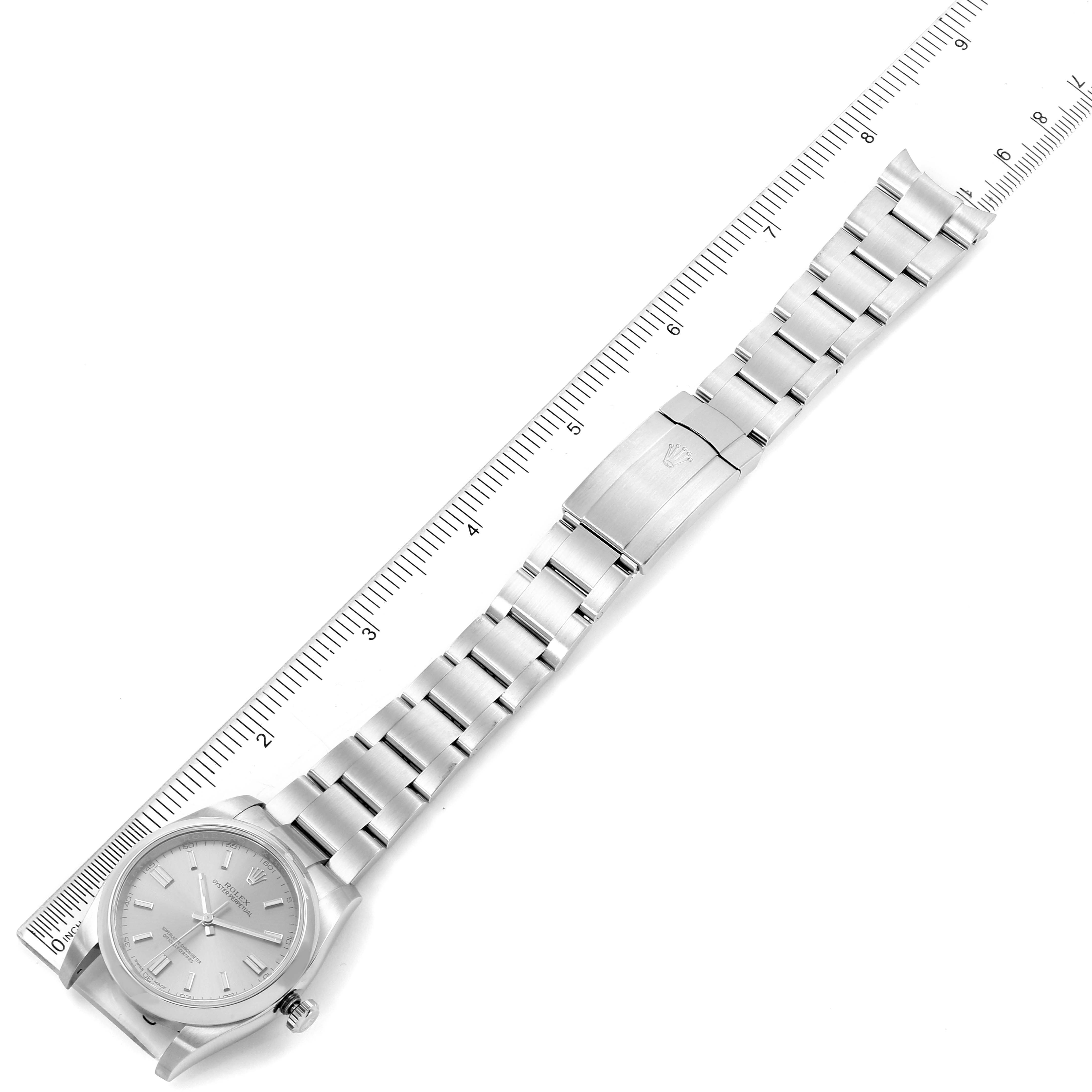 The image shows the full length and clasp of a Rolex Oyster Perpetual 116000 Men
s Stainless Steel Grey Dial 116000 Men
s Stainless Steel Grey Dial watch placed alongside a ruler for size reference.
