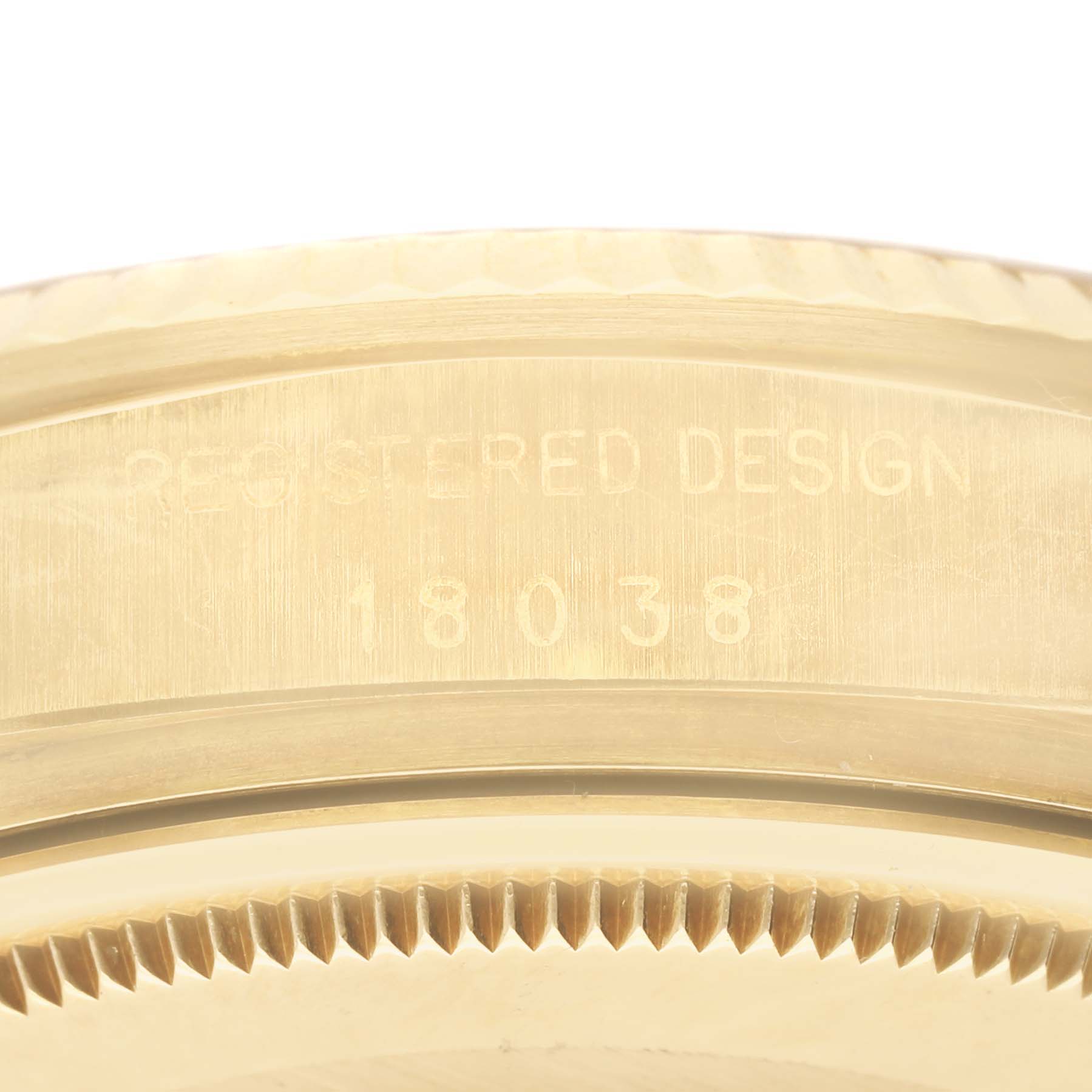 This image shows a close-up of the Rolex President 18038 Men
s Yellow Gold Champagne Dial 18038 Men
s Yellow Gold Champagne Dial model watch
s gold case with the registered design number 18038 engraved.