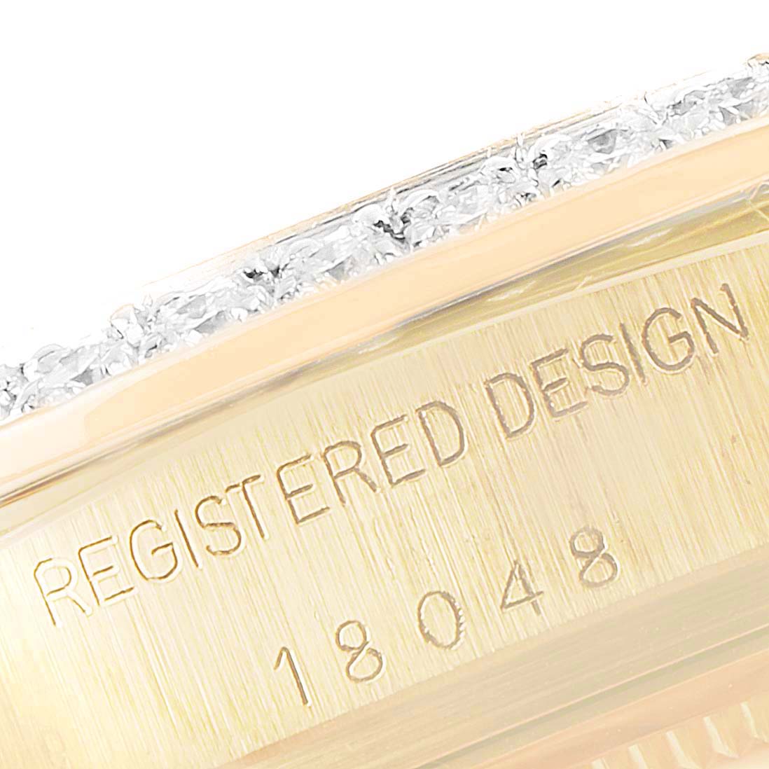 This close-up image of the Rolex President 18048 Men
s Yellow Gold Champagne Dial 18048 Men
s Yellow Gold Champagne Dial watch model 18048 shows part of the engraved bezel and edge of the gem-set dial.