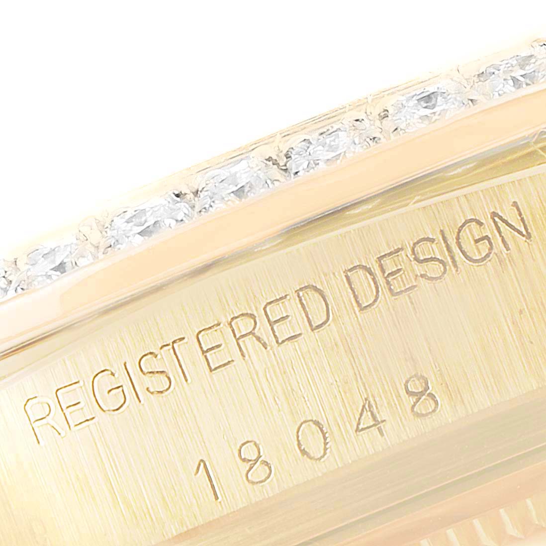 The image shows a close-up of the side of a Rolex President 18048 Men
s Yellow Gold Champagne Dial 18048 Men
s Yellow Gold Champagne Dial watch, highlighting the case with a diamond bezel and engraved serial number.