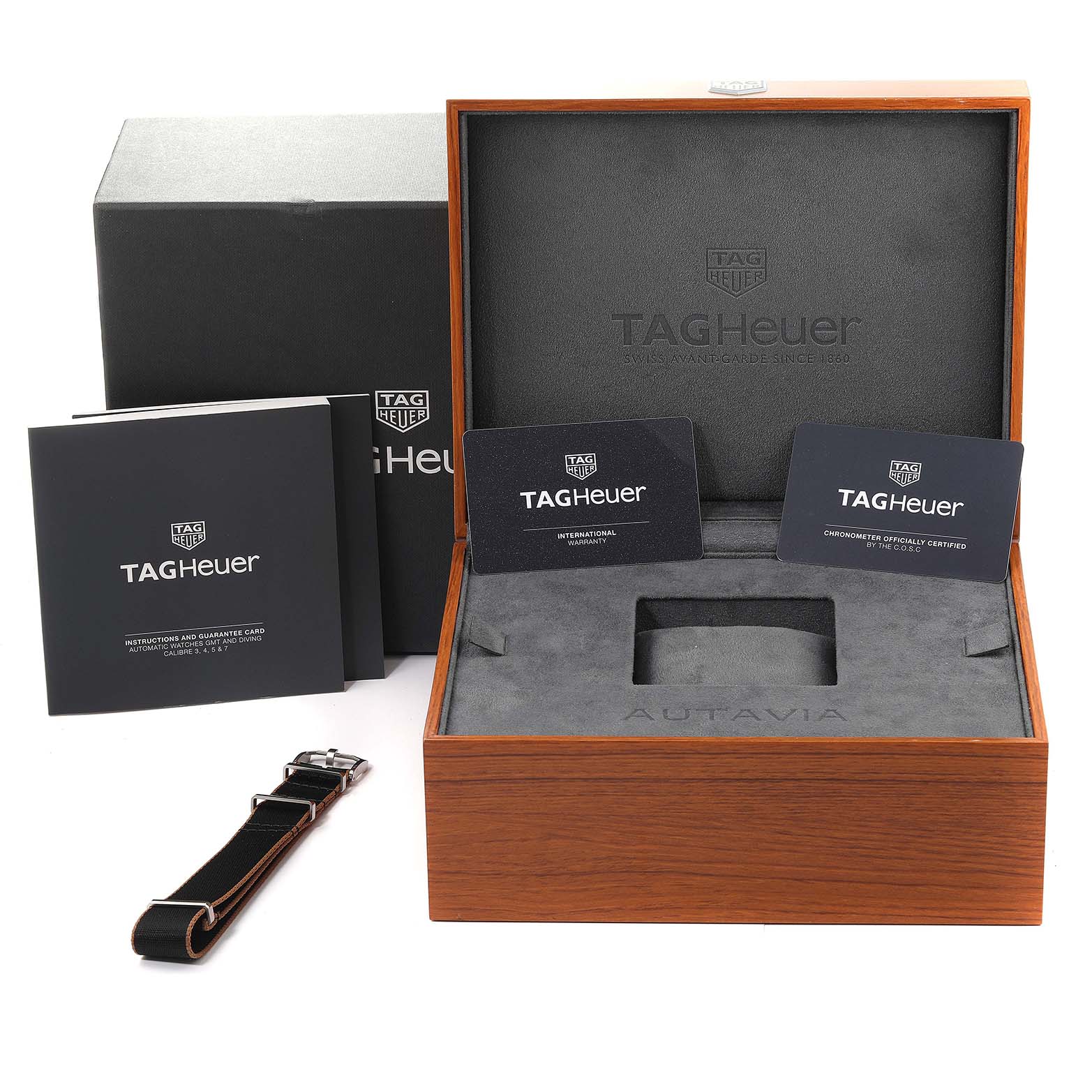The image shows the packaging for a Tag Heuer Autavia WBE5114.EB0173 Men's Stainless Steel Brown Dial WBE5114.EB0173 Men's Stainless Steel Brown Dial, including the box, instruction manual, warranty cards, and a spare strap.