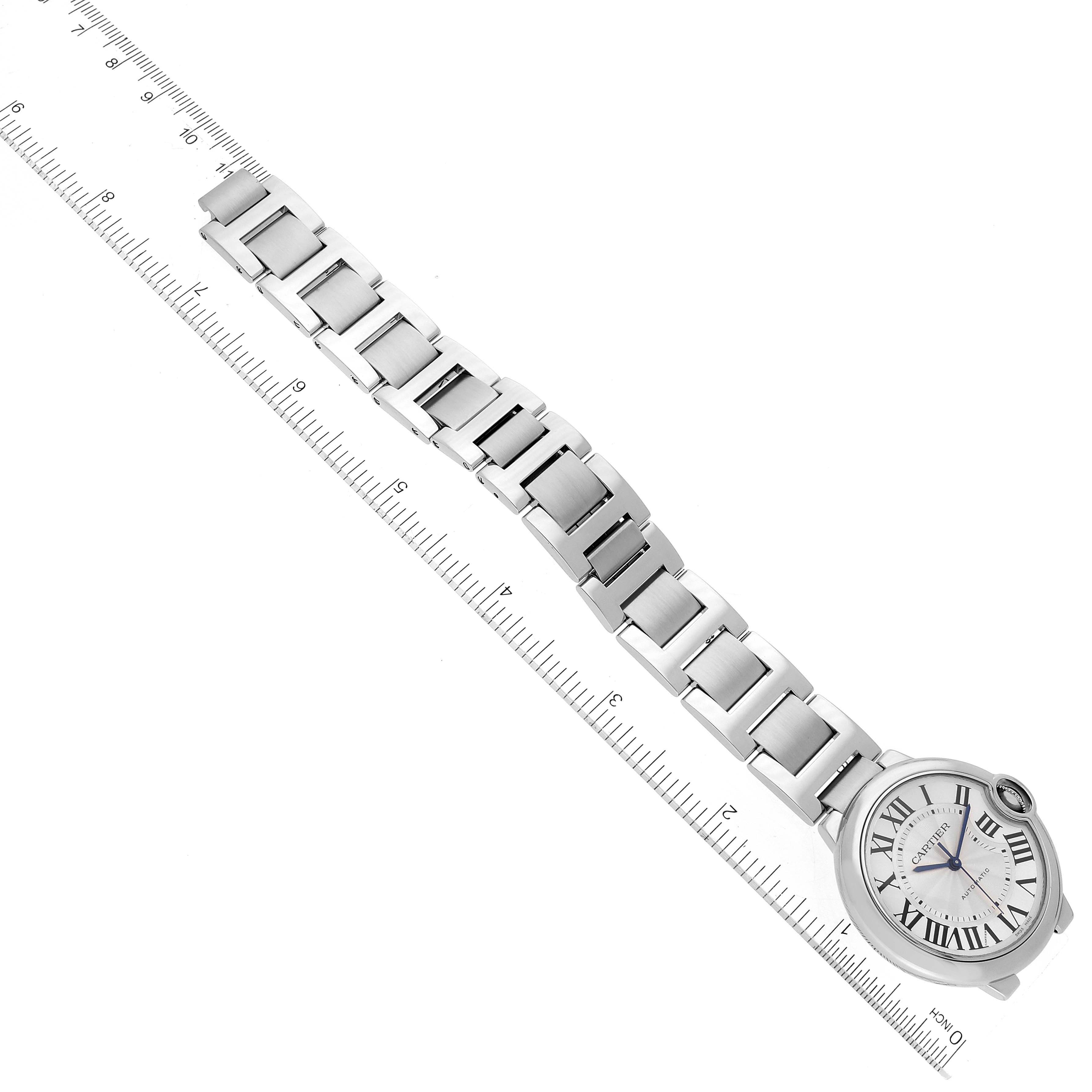 The image shows a top-down view of the Cartier Ballon Bleu W6920046 Women
s Stainless Steel Silver Dial W6920046 Women
s Stainless Steel Silver Dial watch displaying its face, bracelet, and a measuring ruler.