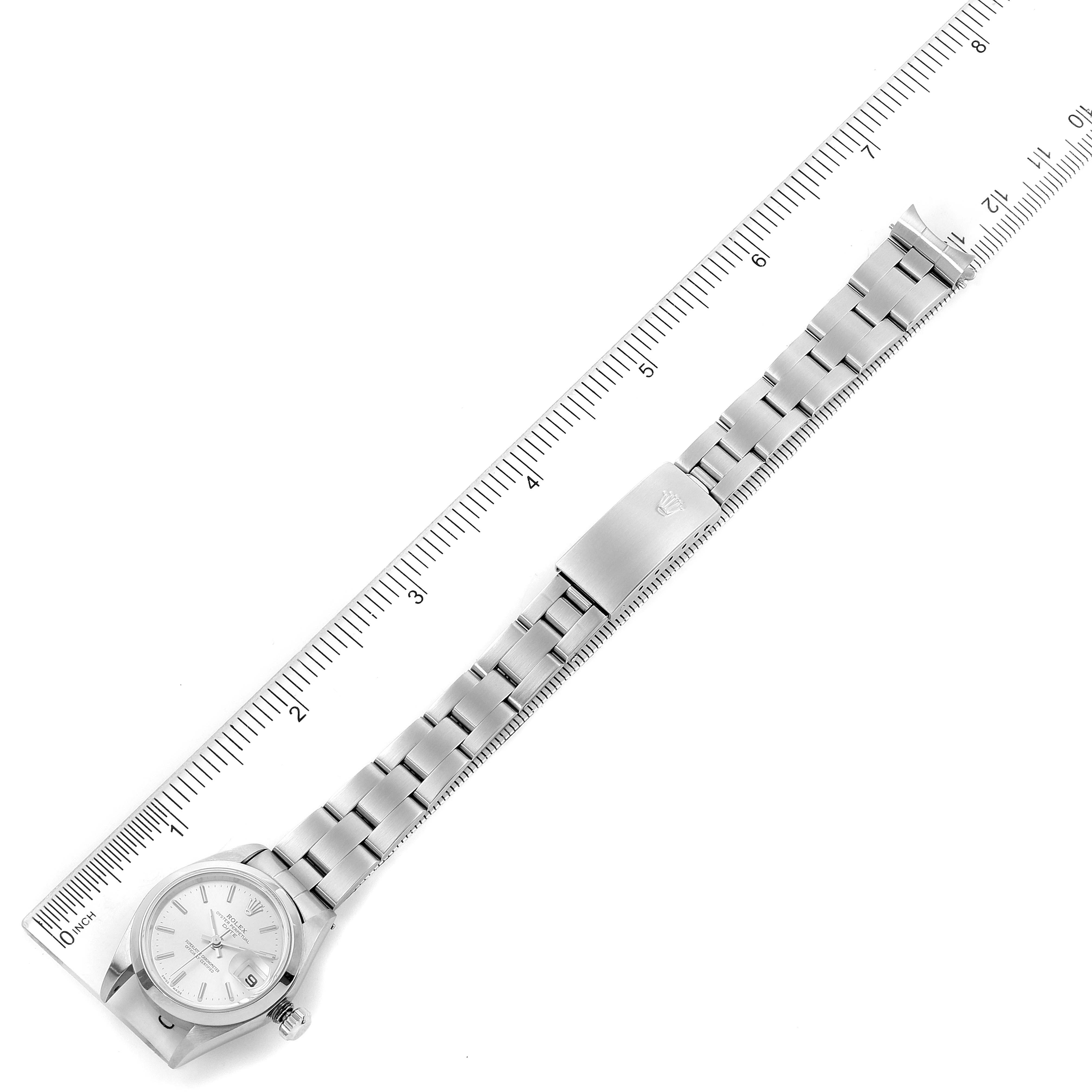 The Rolex Date 79160 Women's Stainless Steel Silver Dial 79160 Women's Stainless Steel Silver Dial watch is shown flat, aligning with a ruler, displaying the face, bracelet, and clasp.