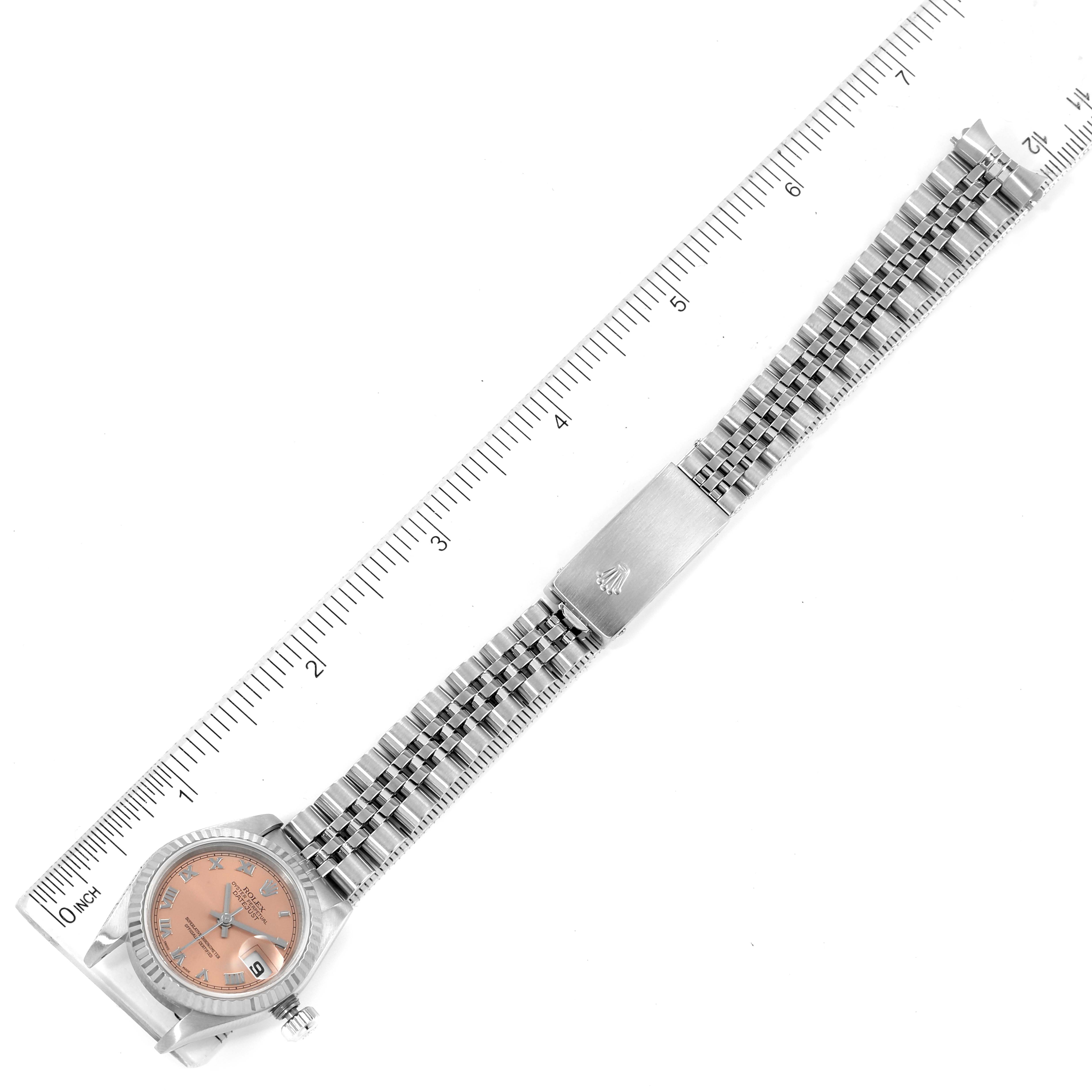 The Rolex Datejust 79174 Women's Stainless Steel Pink Dial 79174 Women's Stainless Steel Pink Dial watch is shown from an overhead angle, displaying the face, bracelet, and clasp, alongside a ruler for scale.