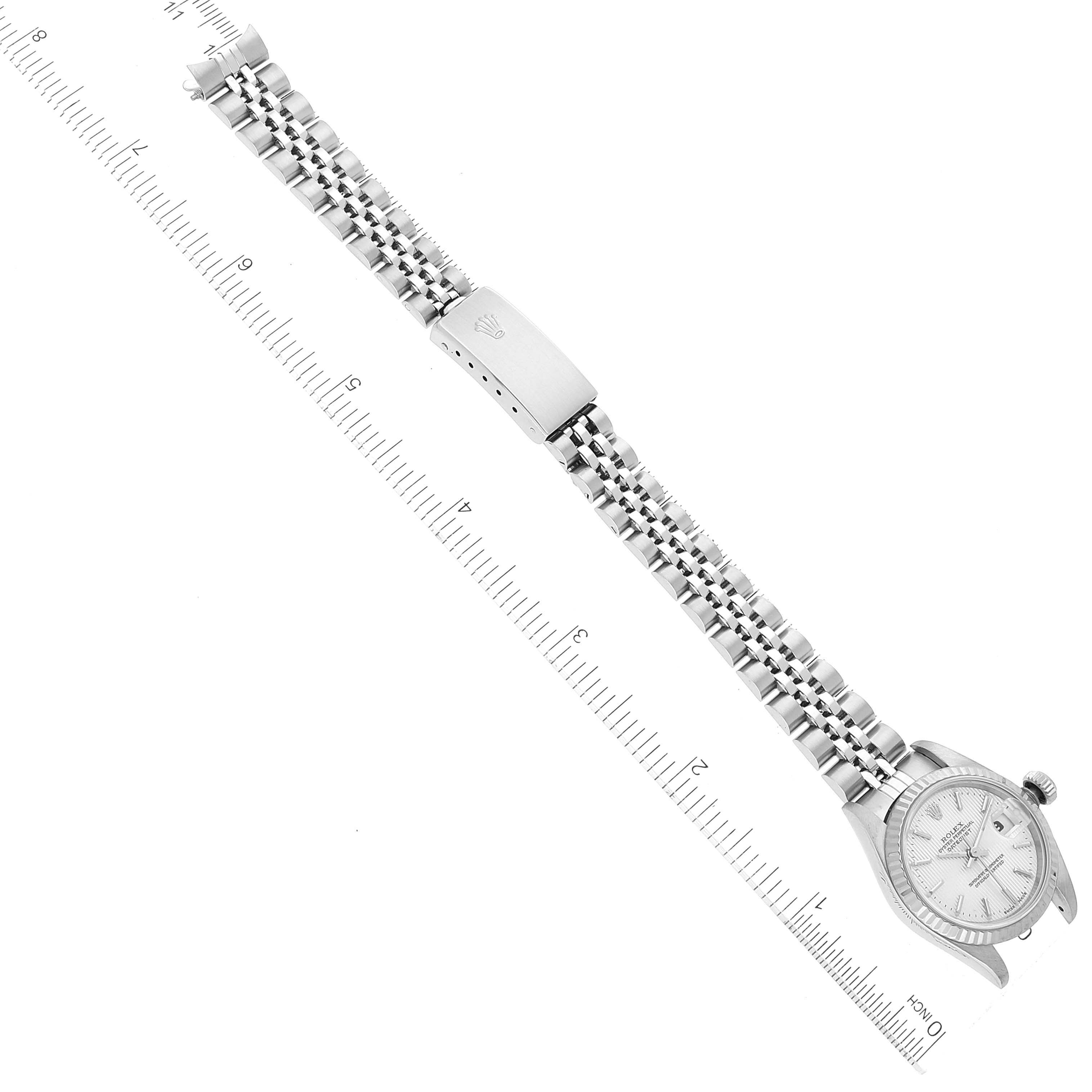 The image shows a top view of a Rolex Datejust 79174 Women's Stainless Steel Silver Dial 79174 Women's Stainless Steel Silver Dial watch, including its face, bracelet, and clasp, with a ruler for scale.