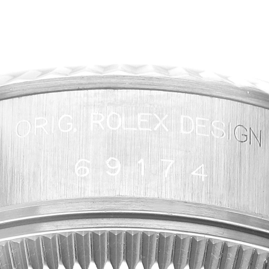 The image shows a close-up of the side engraving and part of the fluted bezel of a Rolex Datejust 69174 Women's Stainless Steel Blue Dial 69174 Women's Stainless Steel Blue Dial watch.