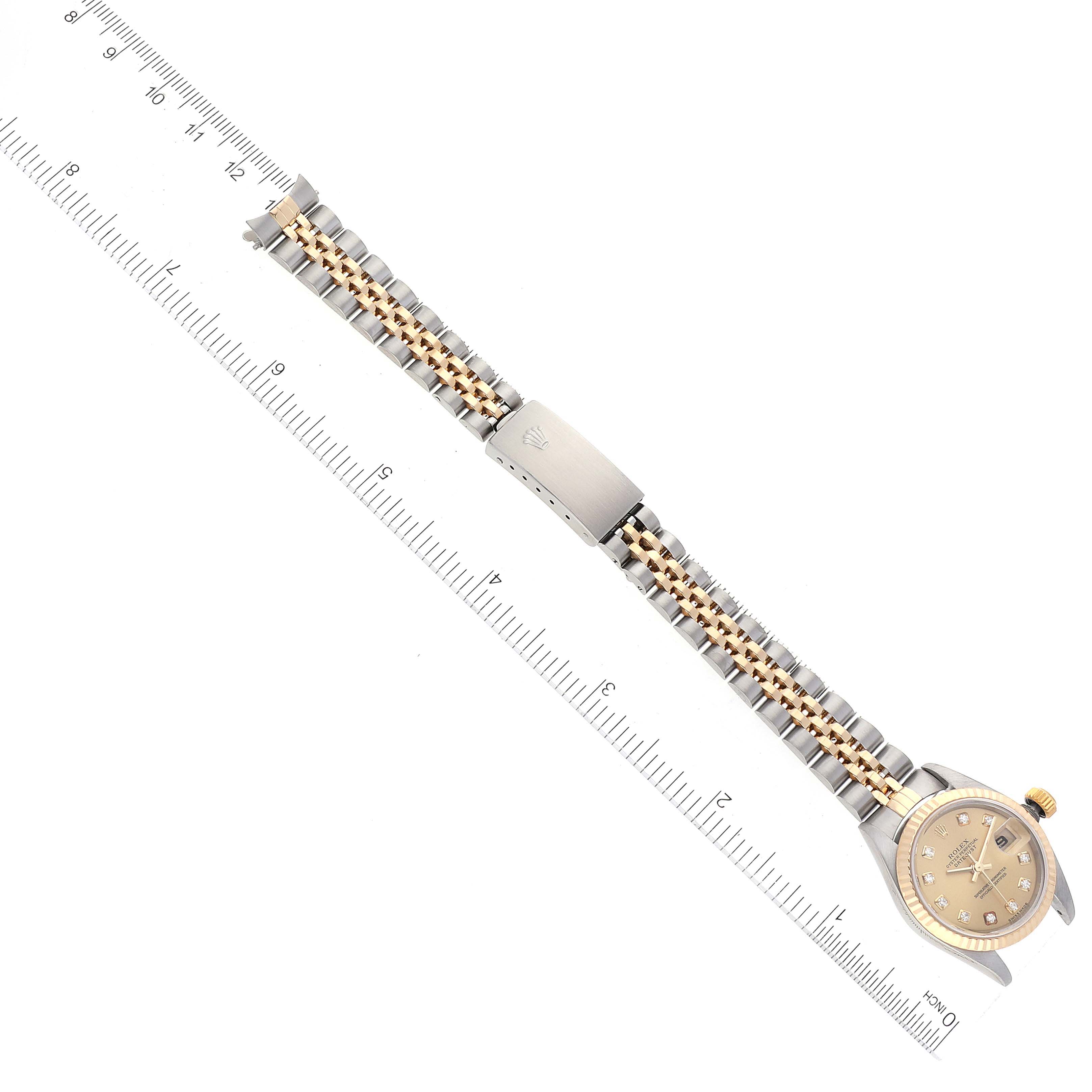 This image shows a top-down view of a Rolex Datejust 79173 Women's Steel and Gold (two tone) Champagne Dial 79173 Women's Steel and Gold (two tone) Champagne Dial watch, with the face, bracelet, and clasp visible alongside a ruler for scale.