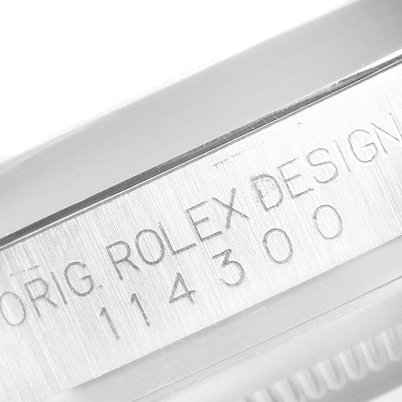 The image shows a close-up of the engravings on the side of the Rolex Oyster Perpetual 114300 Men's Stainless Steel Grey Dial 114300 Men's Stainless Steel Grey Dial model 114300.