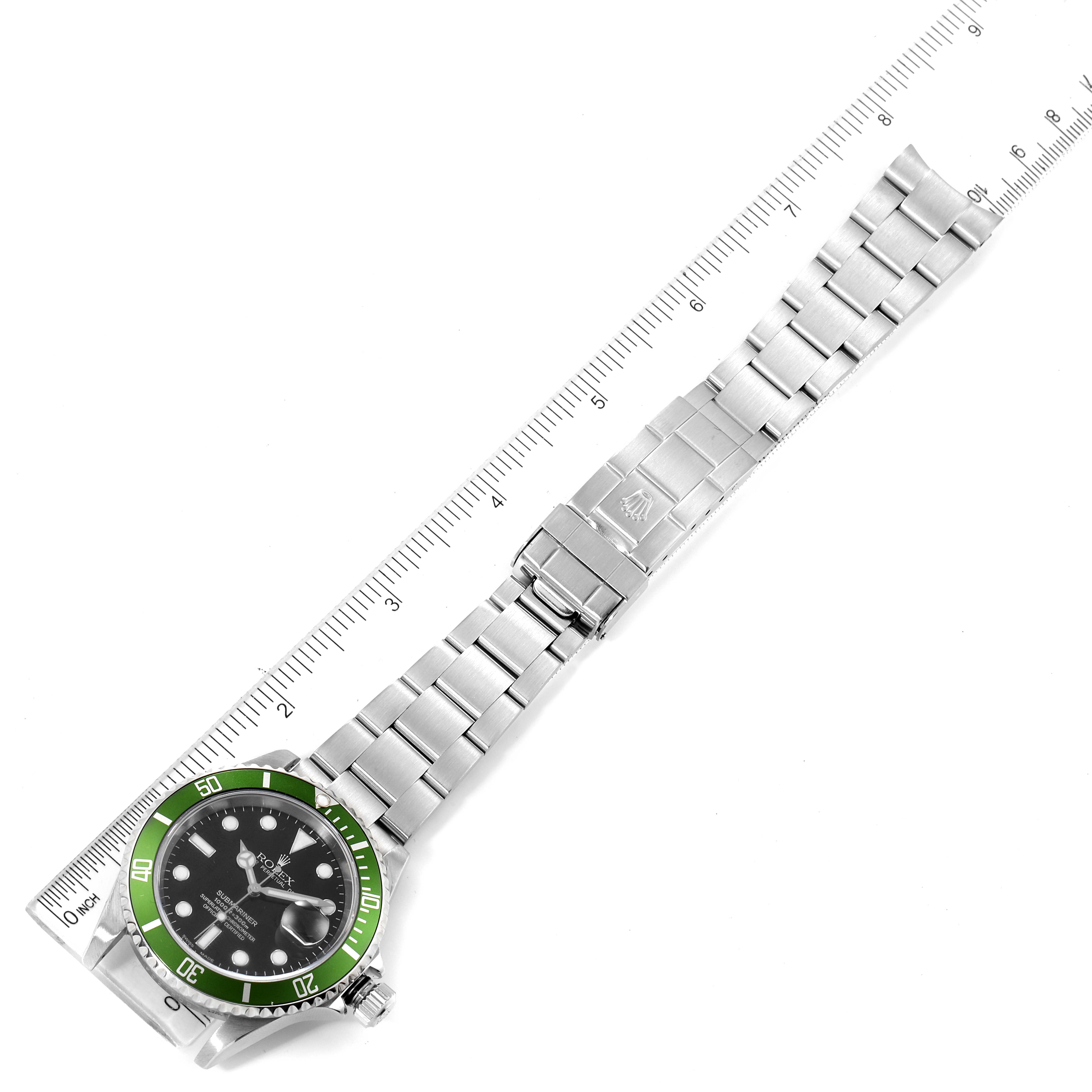 The image shows a Rolex Submariner 16610LV Men
s Stainless Steel Black Dial 16610LV Men
s Stainless Steel Black Dial watch laid flat with a measuring ruler, displaying the face, bracelet, and clasp.