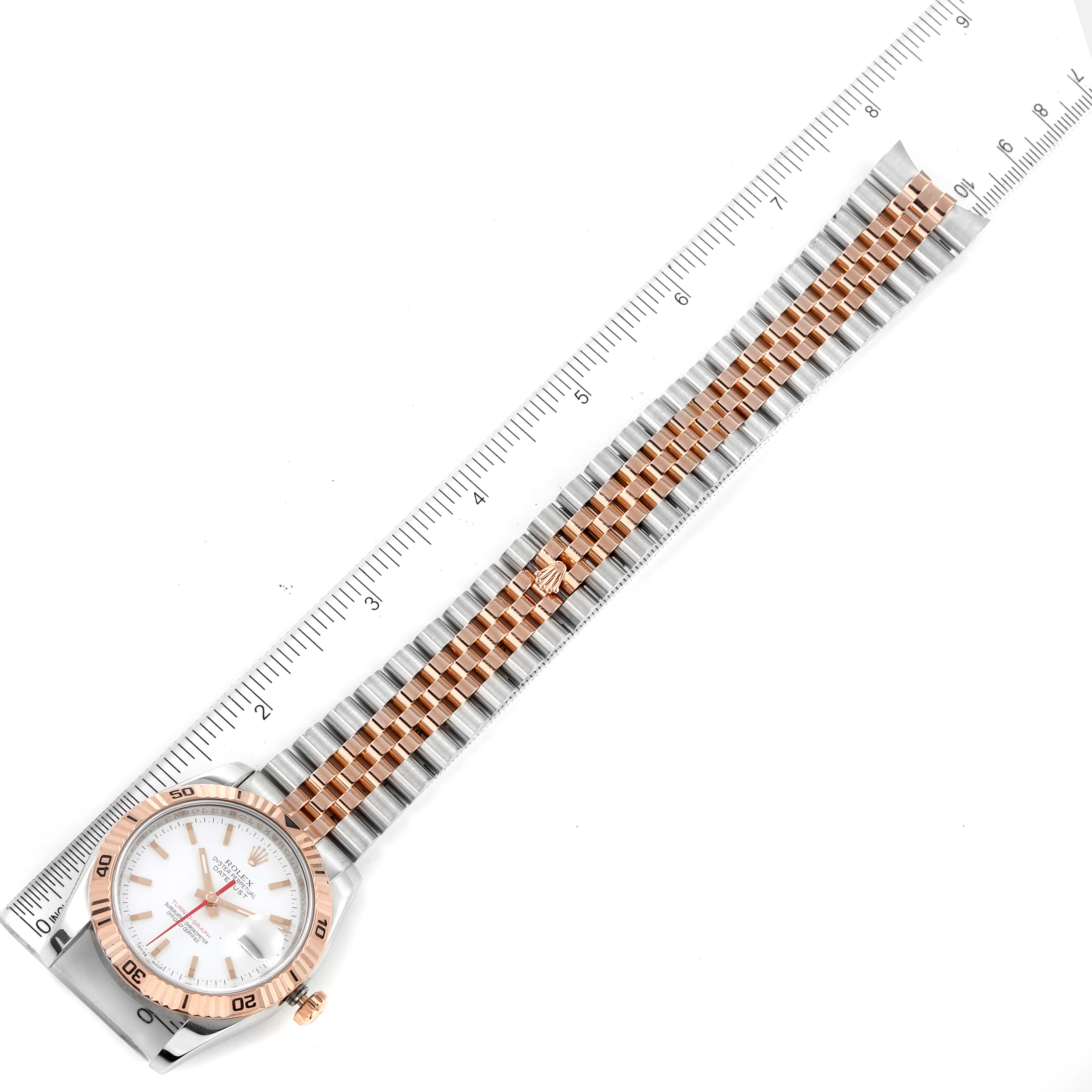 The Rolex Turn-o-Graph 116261 Men's Steel and Gold (two tone) White Dial 116261 Men's Steel and Gold (two tone) White Dial watch is shown from an angled top-down view, showing the entire bracelet and the face with a ruler alongside.