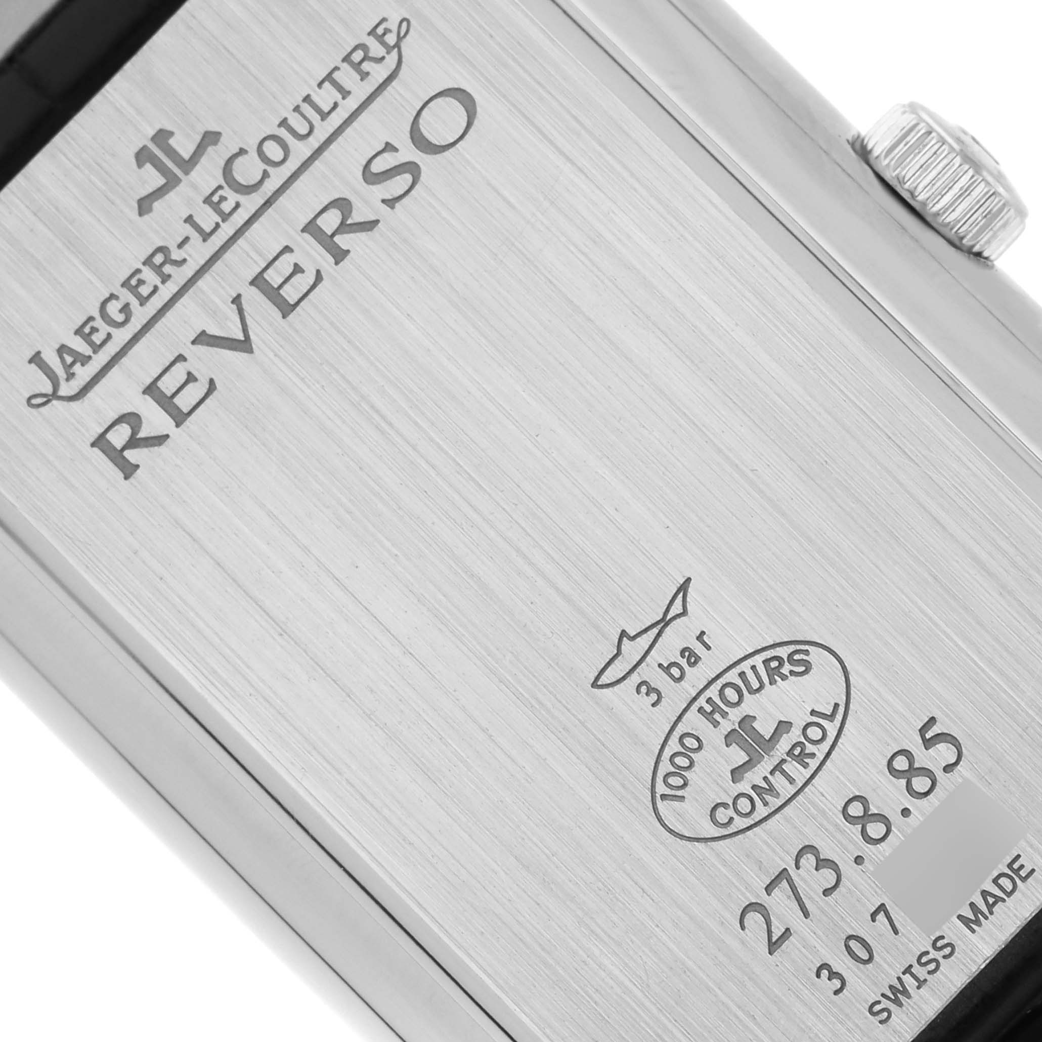 The image shows the reverse side of a Jaeger-LeCoultre Reverso watch, displaying the brand, model name, and specification engravings.