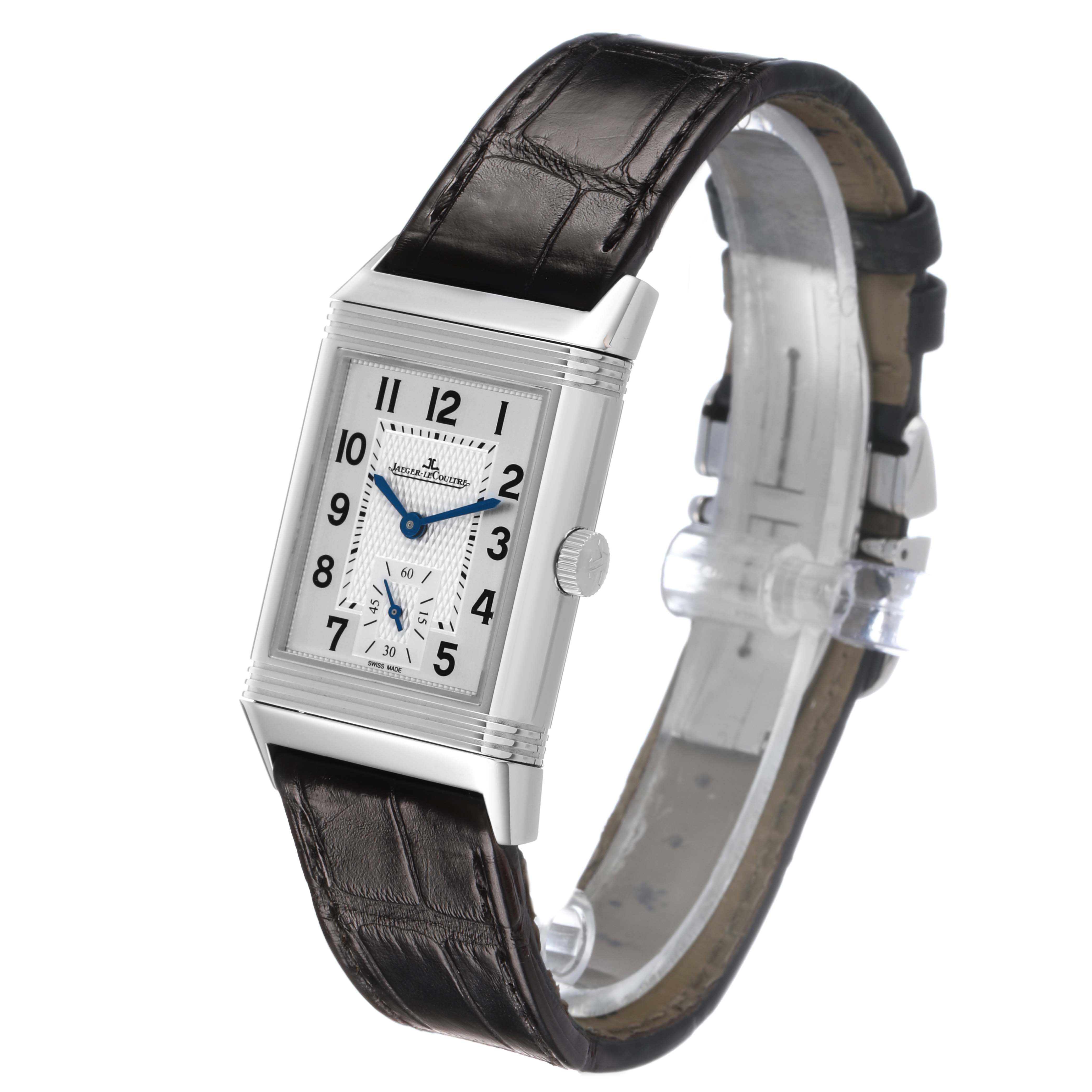 The Jaeger-LeCoultre Reverso watch is shown at an angle displaying the face, leather strap, and clasp.