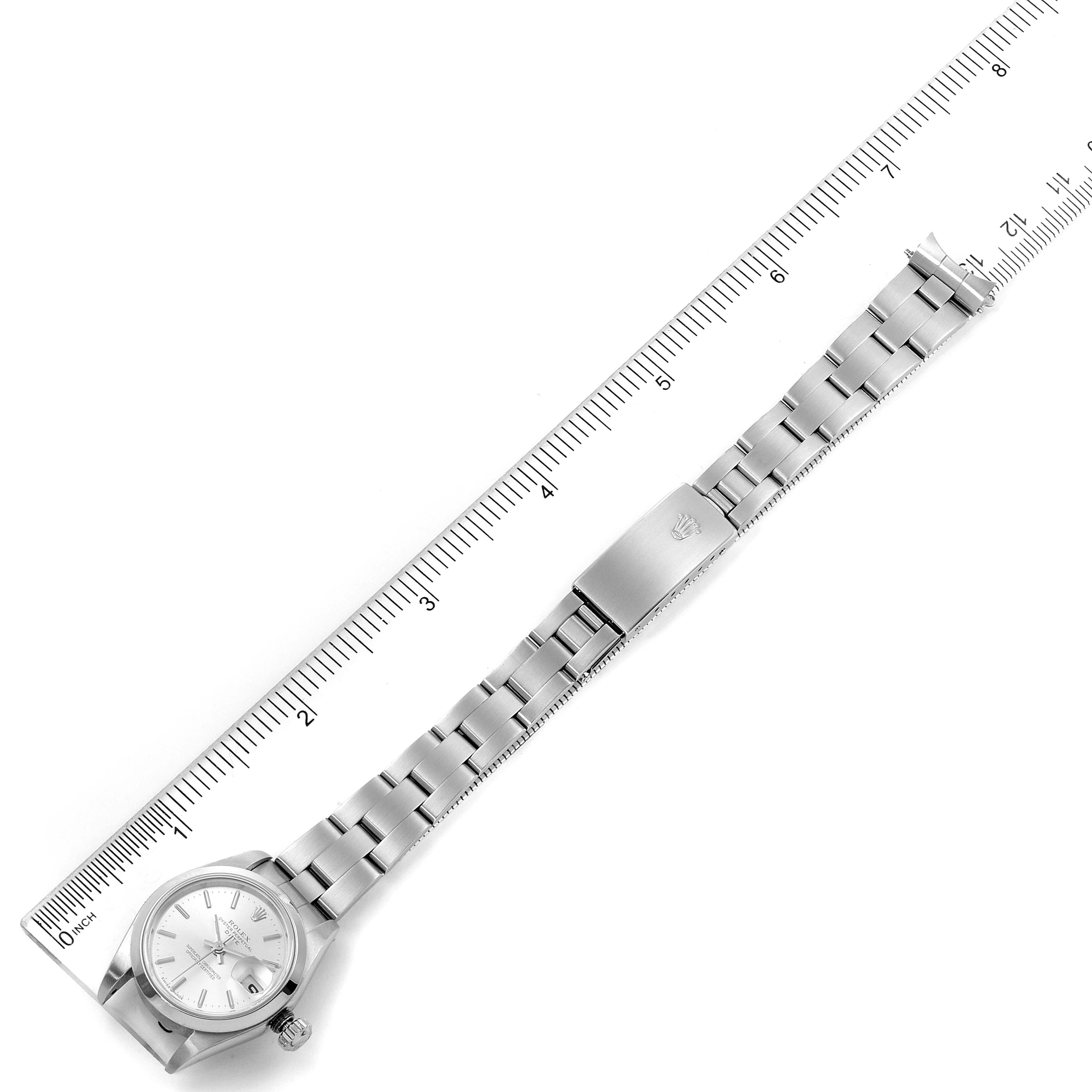 The image shows a Rolex Date 79160 Women's Stainless Steel Silver Dial 79160 Women's Stainless Steel Silver Dial model watch laid flat next to a ruler, displaying its face, bracelet, and clasp.