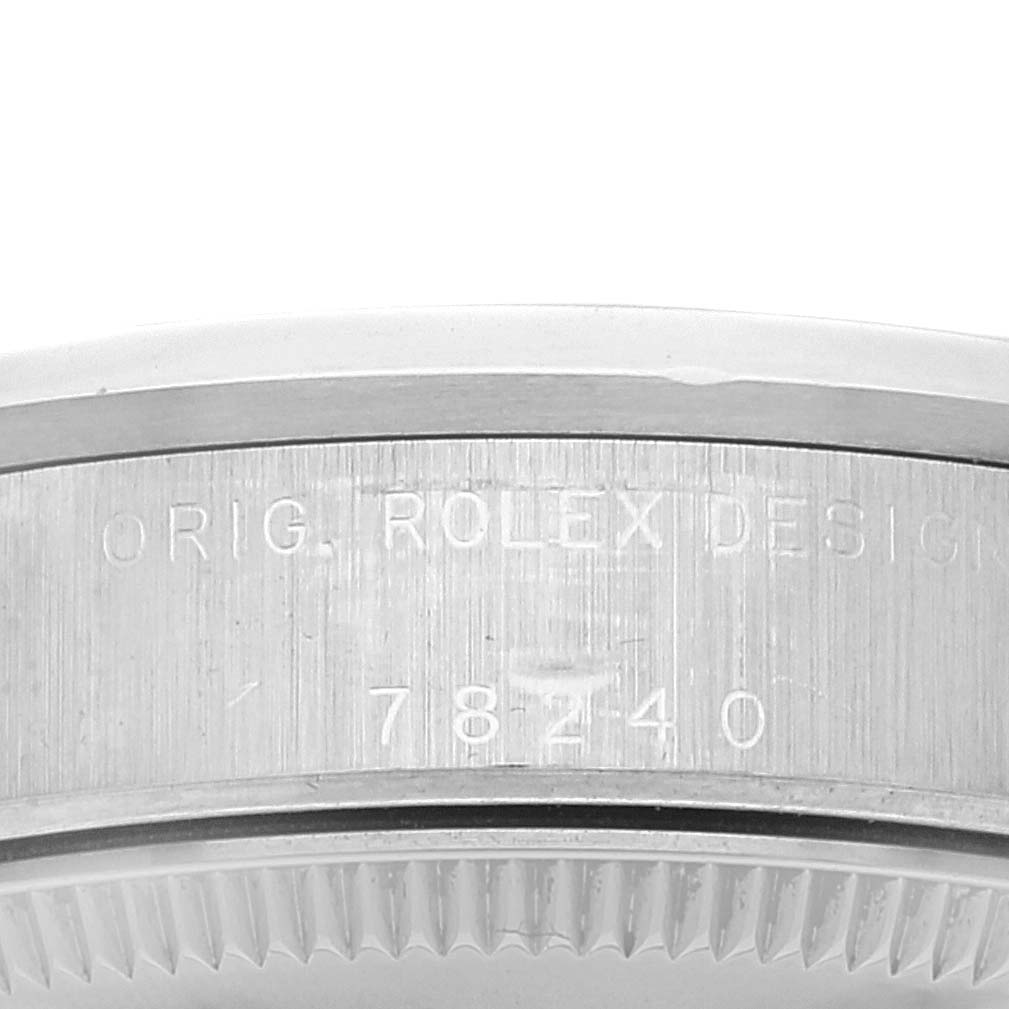 The image shows a close-up of the side of the mid-size Rolex watch, highlighting the engraved serial number and design text.