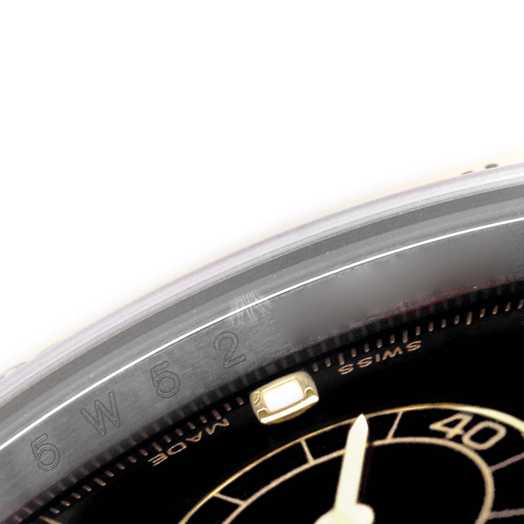 The image shows a close-up angle of the bezel and dial edge of a Rolex Daytona 116523 Men's Steel and Gold (two tone) Black Dial watch, highlighting numerals and part of the minute track.