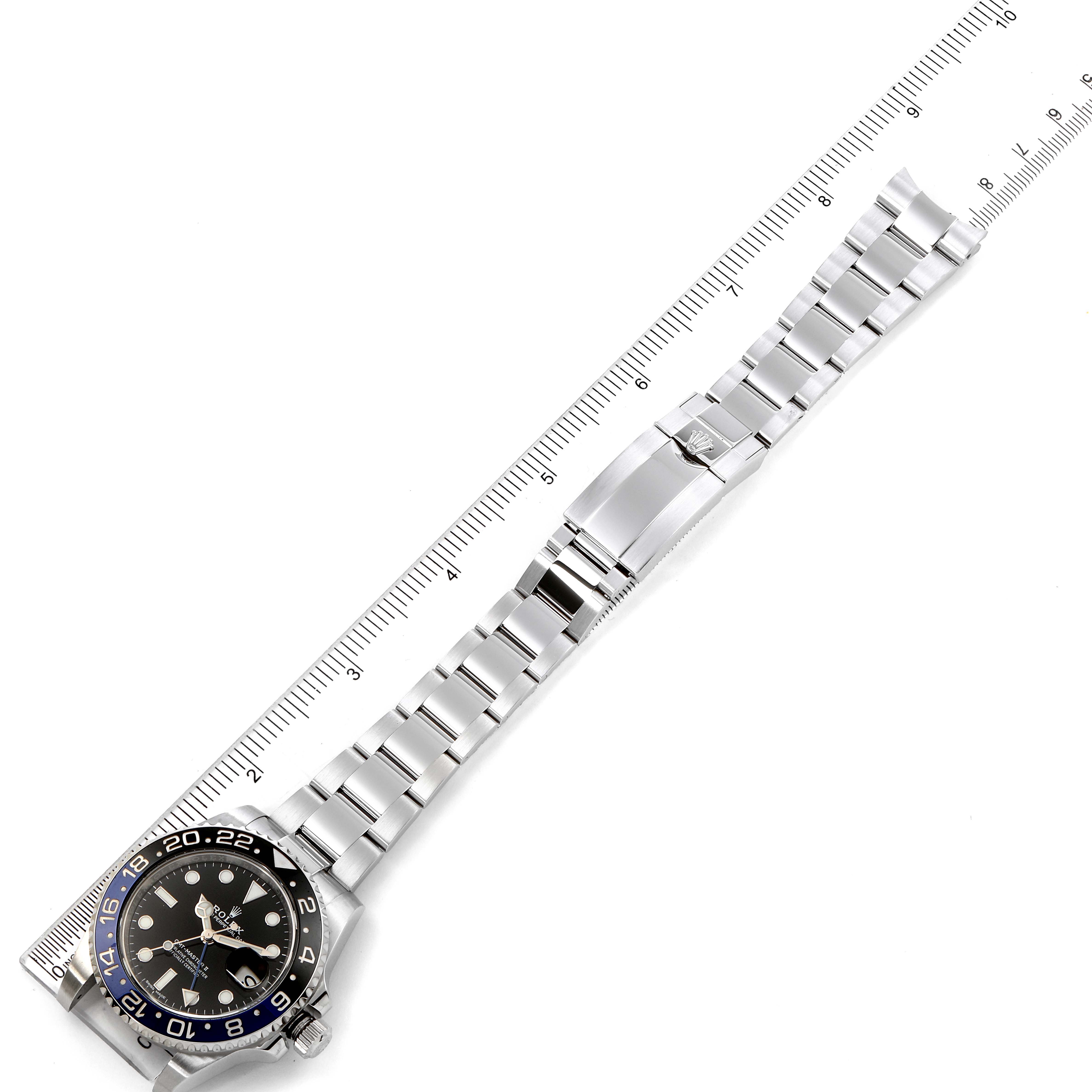 The image shows a Rolex GMT-Master 116710 Men
s Stainless Steel Black Dial 116710 Men
s Stainless Steel Black Dial watch laid flat, highlighting its metallic bracelet, clasp, and bezel with a ruler for scale.
