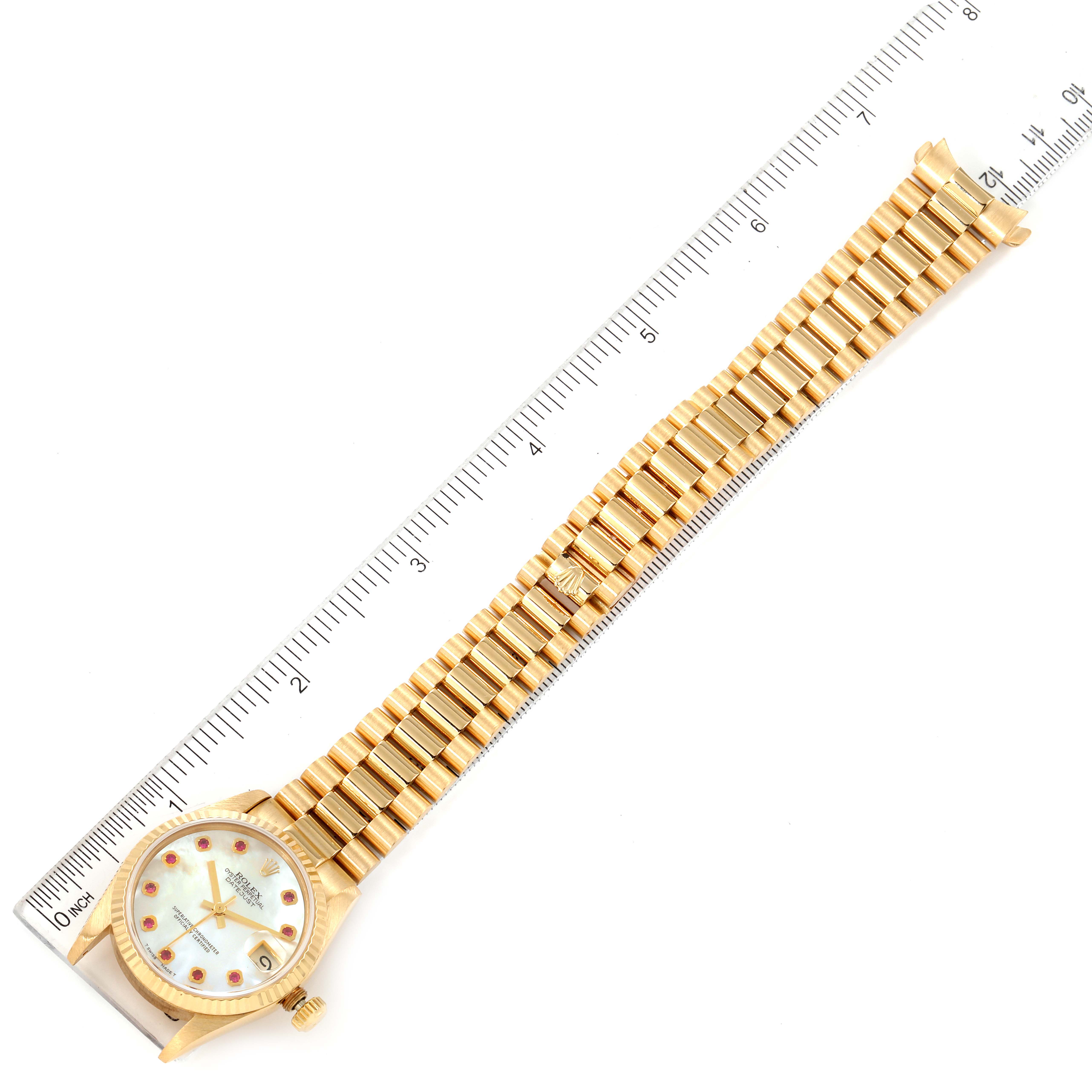 The Rolex President 68278 Women's Yellow Gold Mother of Pearl Dial 68278 Women's Yellow Gold Mother of Pearl Dial model watch is shown from the top view, displaying its face, bezel, and full bracelet against a measuring ruler.