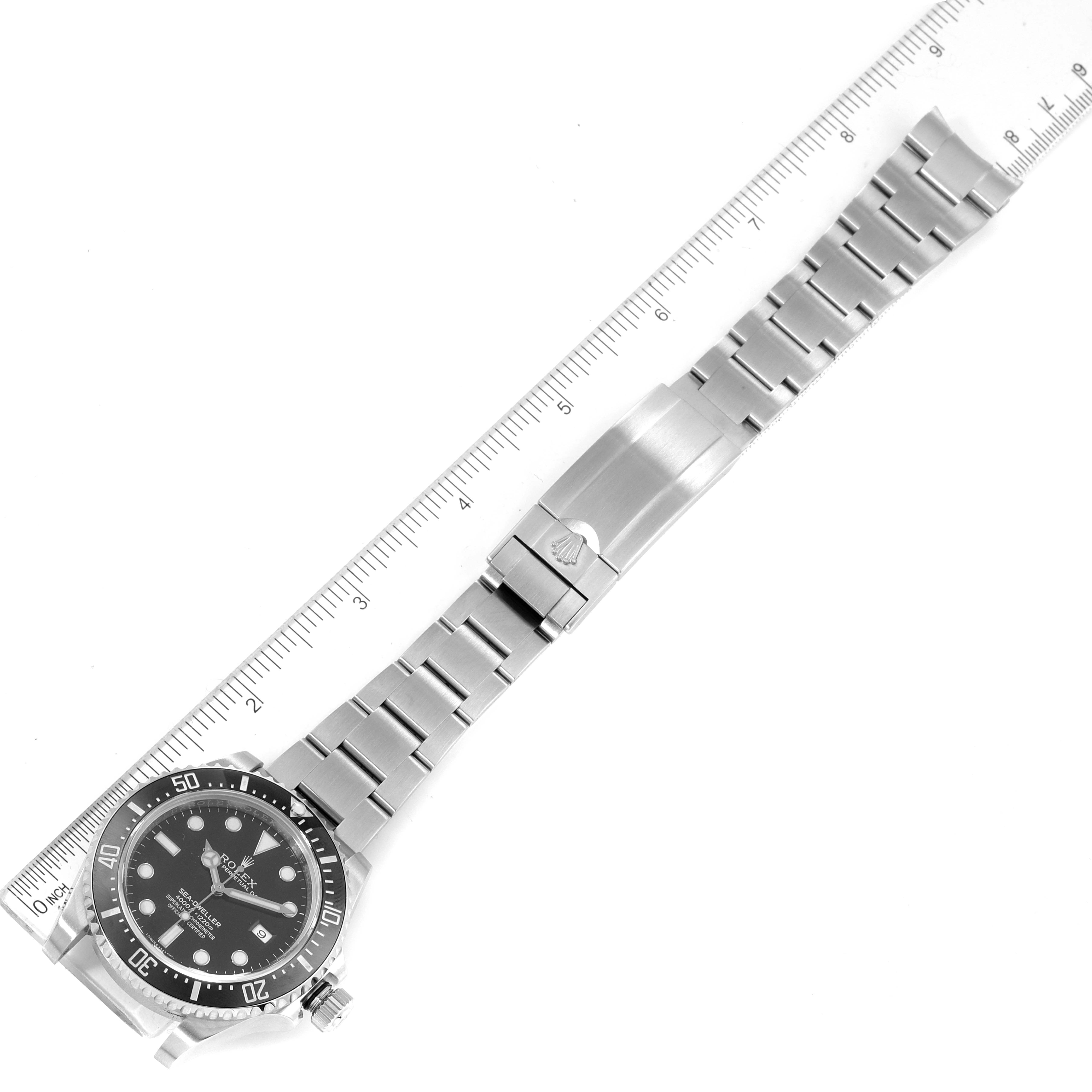 The image shows the Rolex Sea-Dweller 116600 Men's Stainless Steel Black Dial 116600 Men's Stainless Steel Black Dial watch laid flat, displaying the face and full bracelet alongside a ruler.