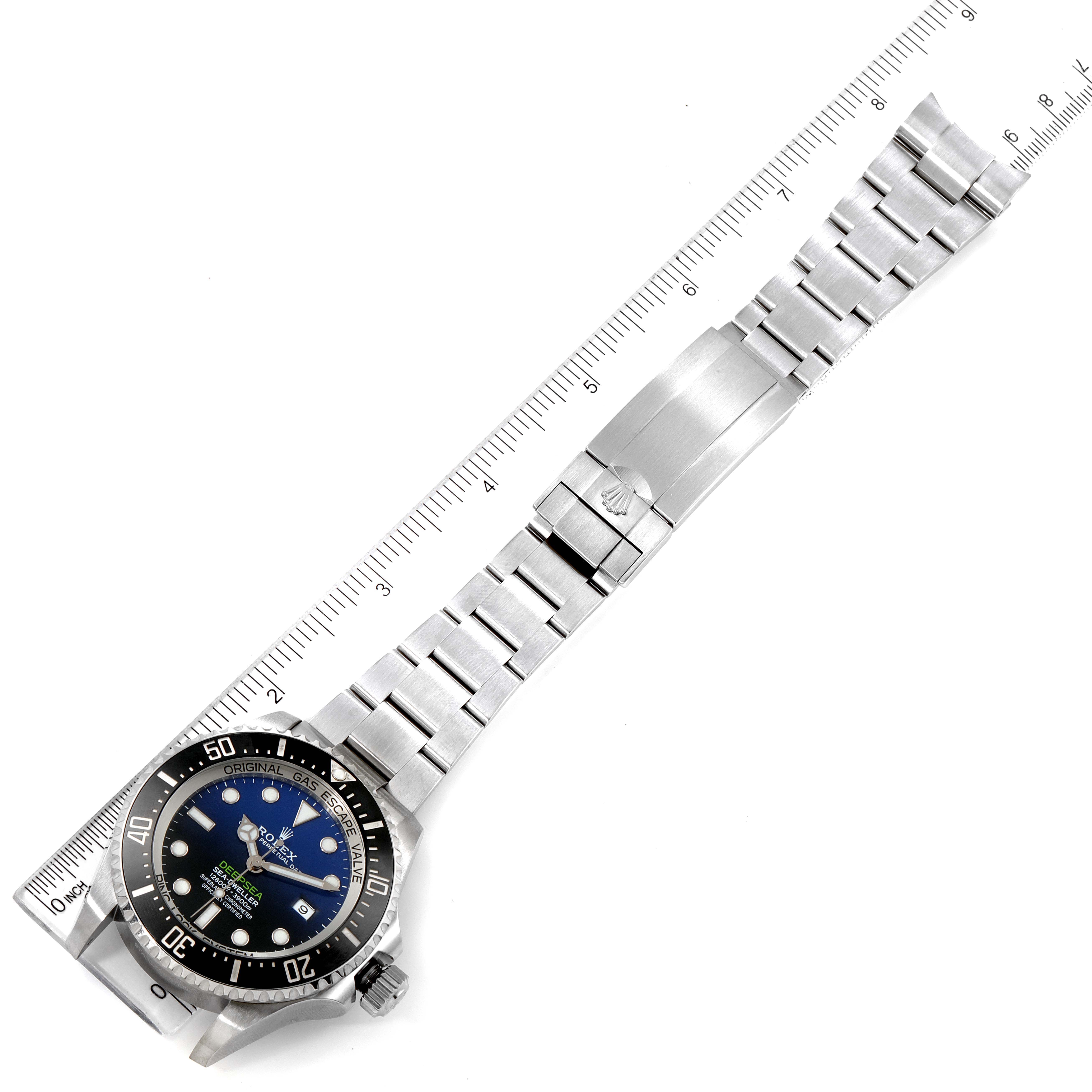 The image shows a top-down view of a Rolex Sea-Dweller 126660 Men
s Stainless Steel Blue Dial 126660 Men
s Stainless Steel Blue Dial watch with a stainless steel bracelet and a ruler for scale.