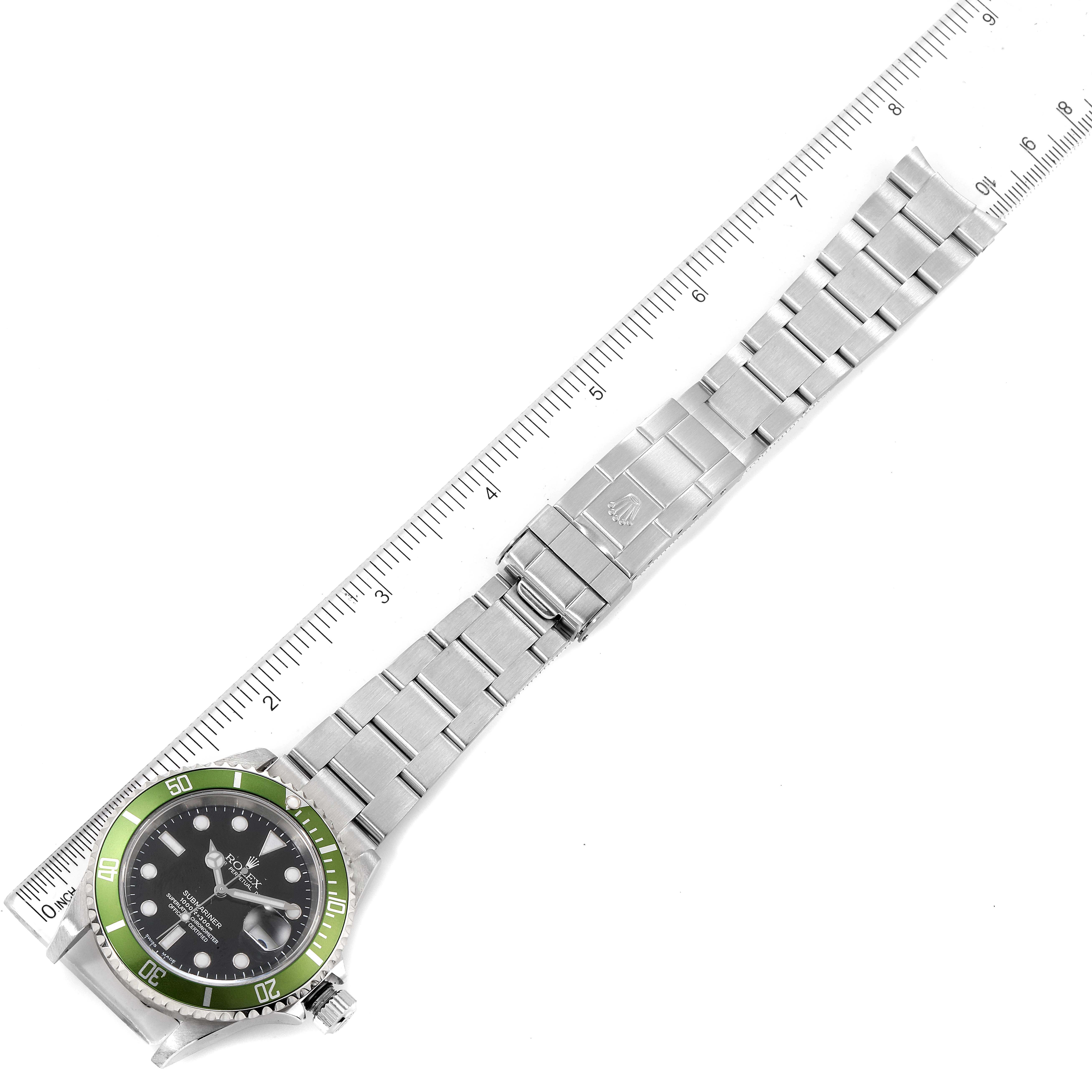 The image shows a top view of a Rolex Submariner 16610LV Men's Stainless Steel Black Dial 16610LV Men's Stainless Steel Black Dial watch, highlighting its stainless steel bracelet and green bezel, alongside a ruler.